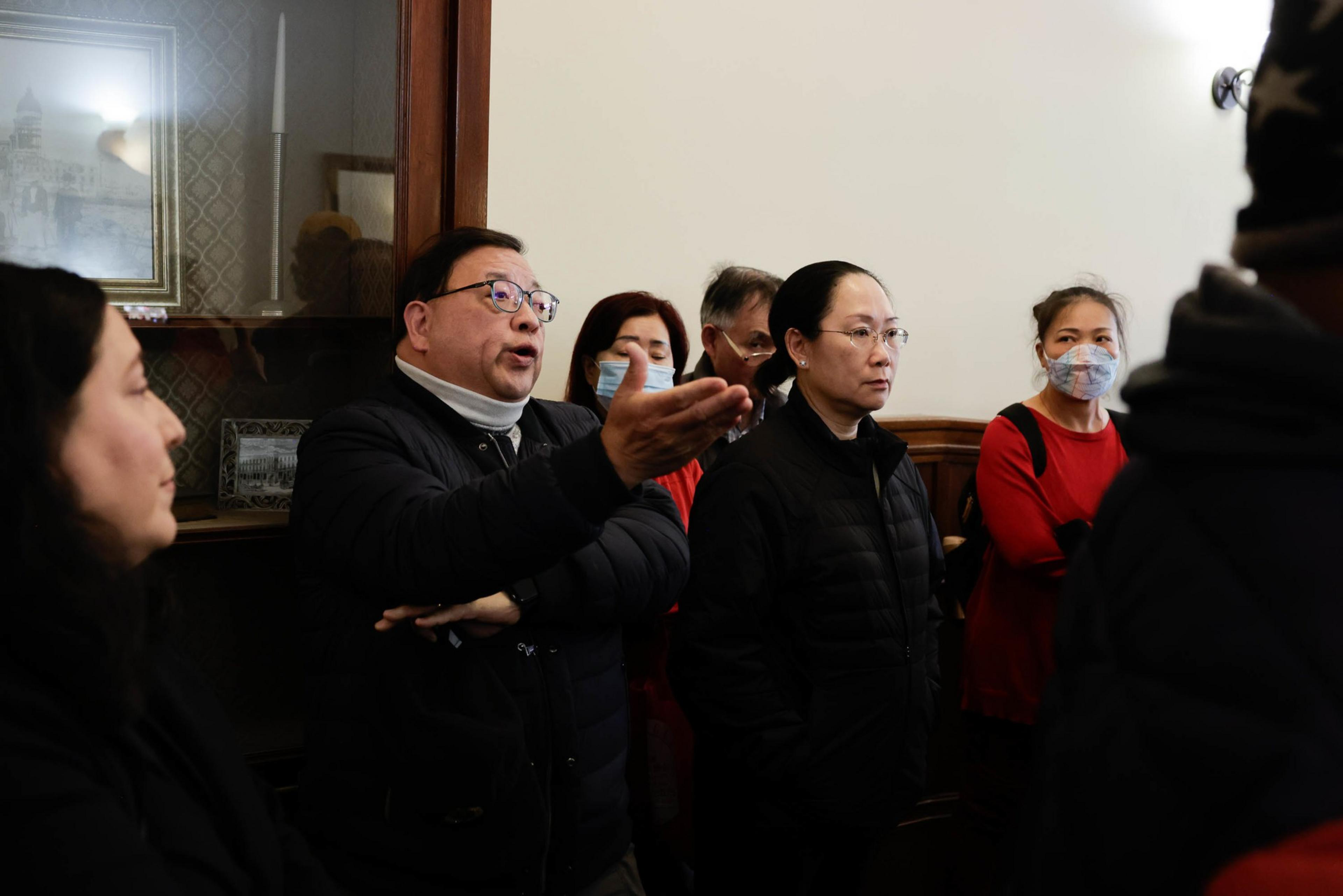 a group of people stand in the back of a room looking frustrated. 