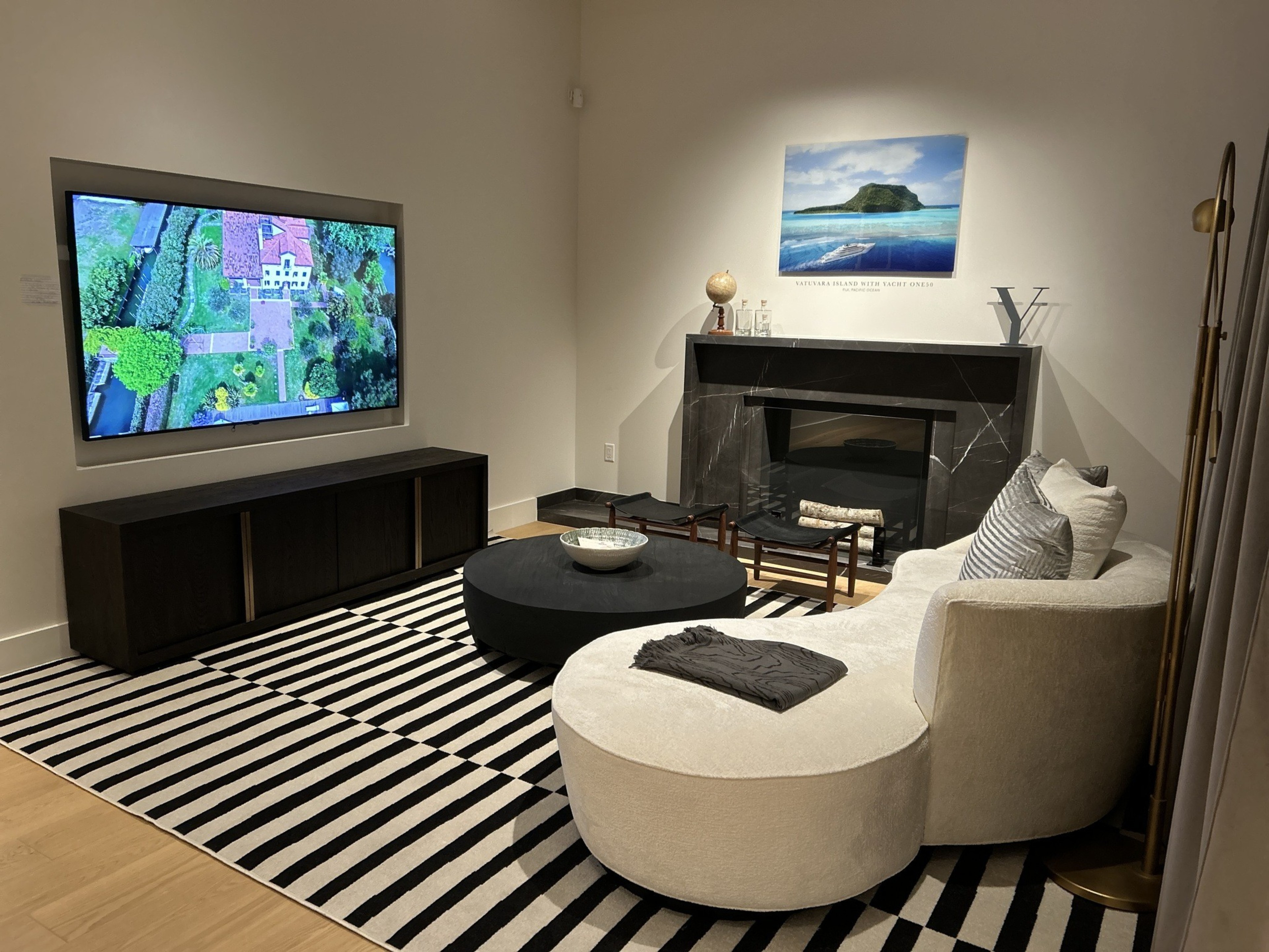 a mock living room complete with striped rug, bigscreen tv and chairs