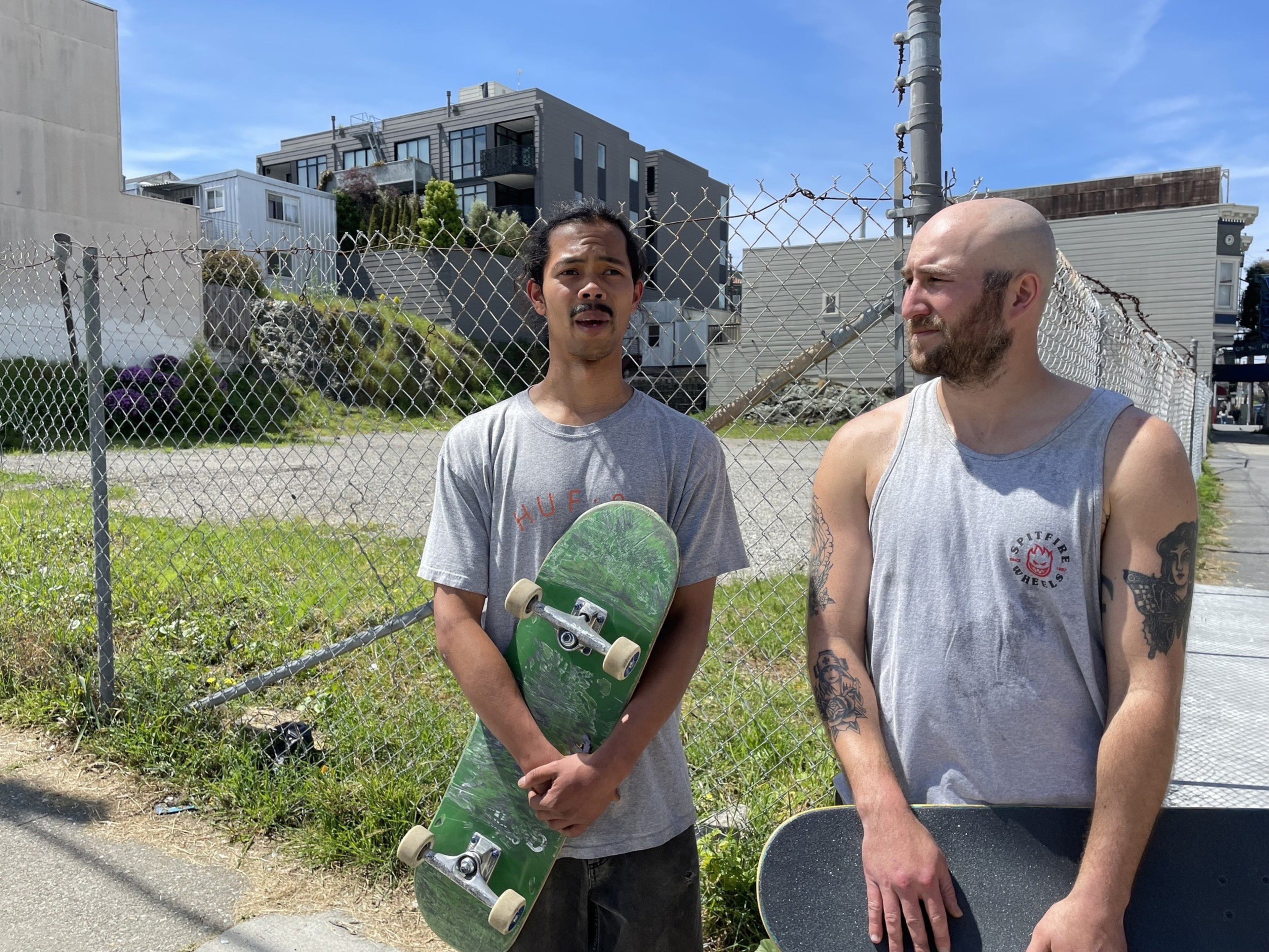 Two men stand holding skateboards in a photo.