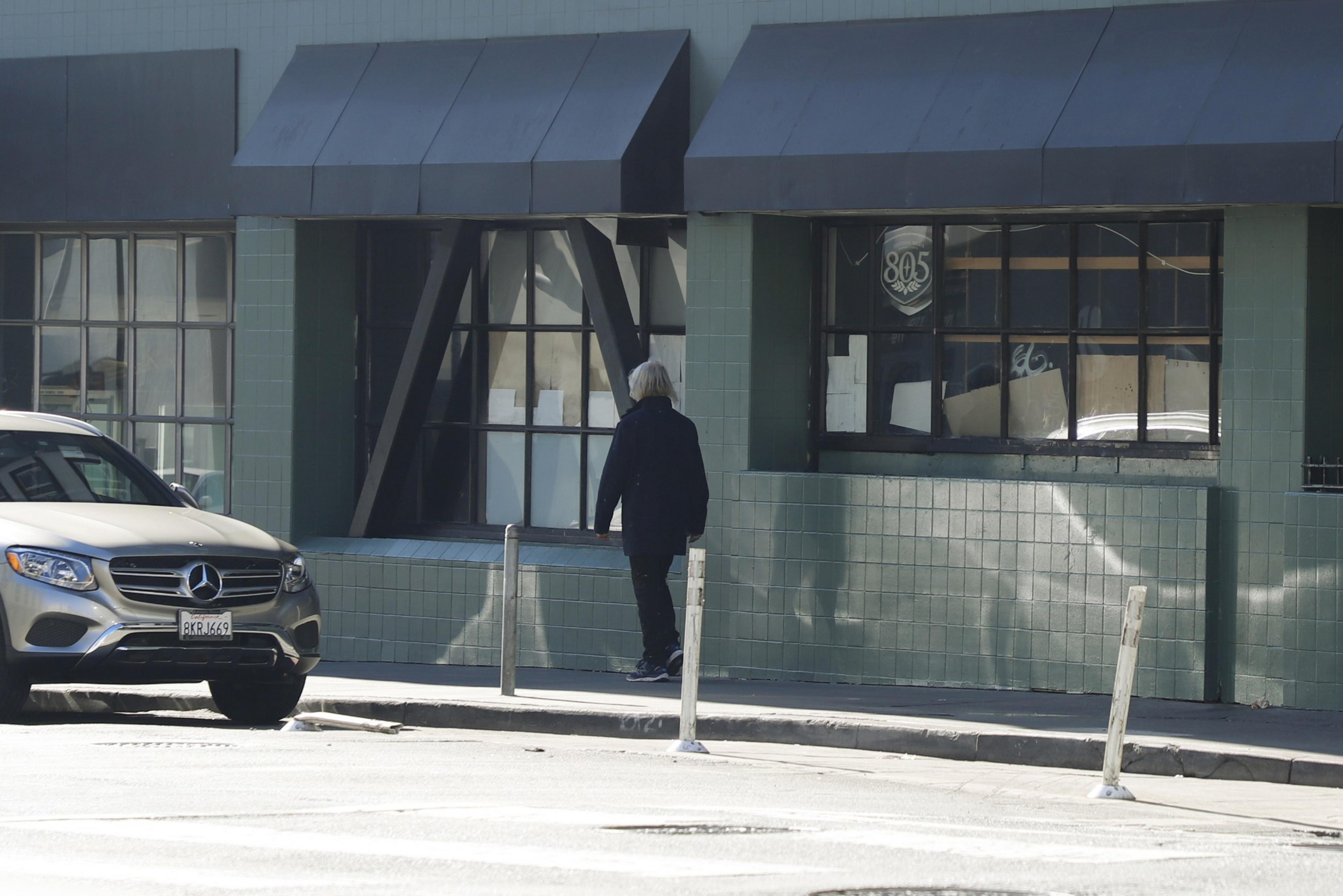 A pedestrian walks down an empty city sidewalk on a sunny day.