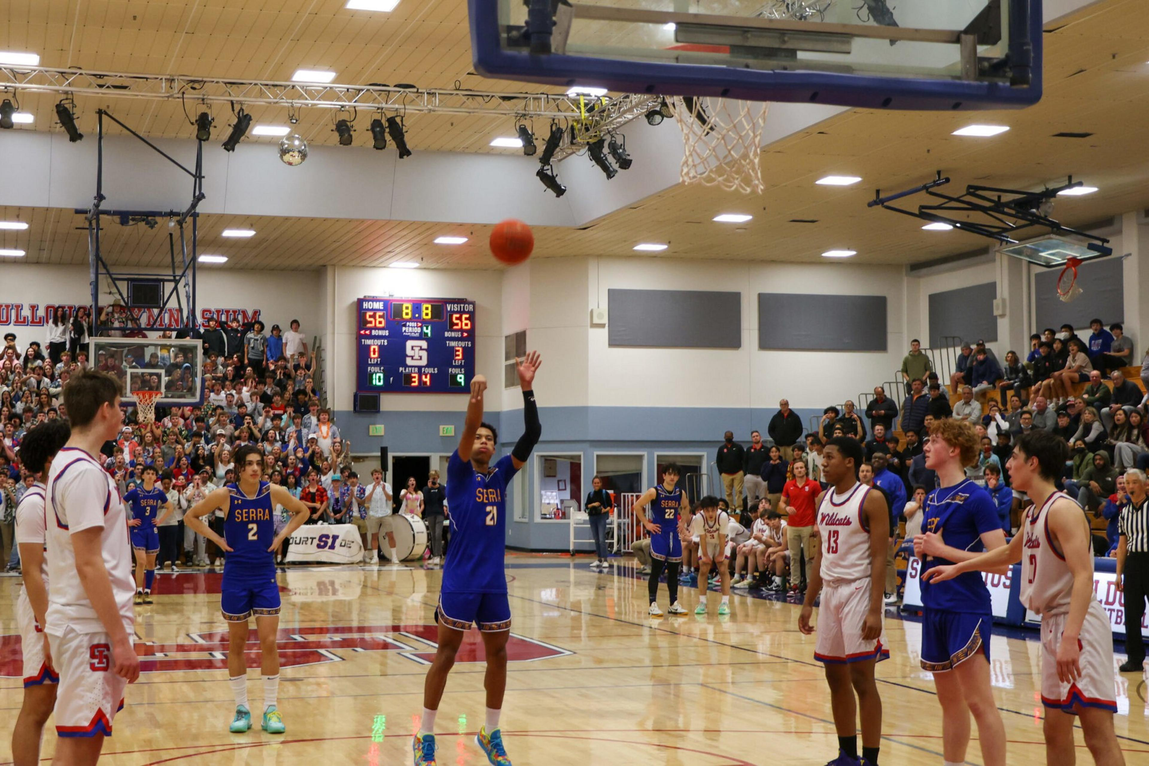 A player in a blue jersey shoots a free throw during a tied basketball game with 8.8 seconds left, while players and a crowd watch intently.
