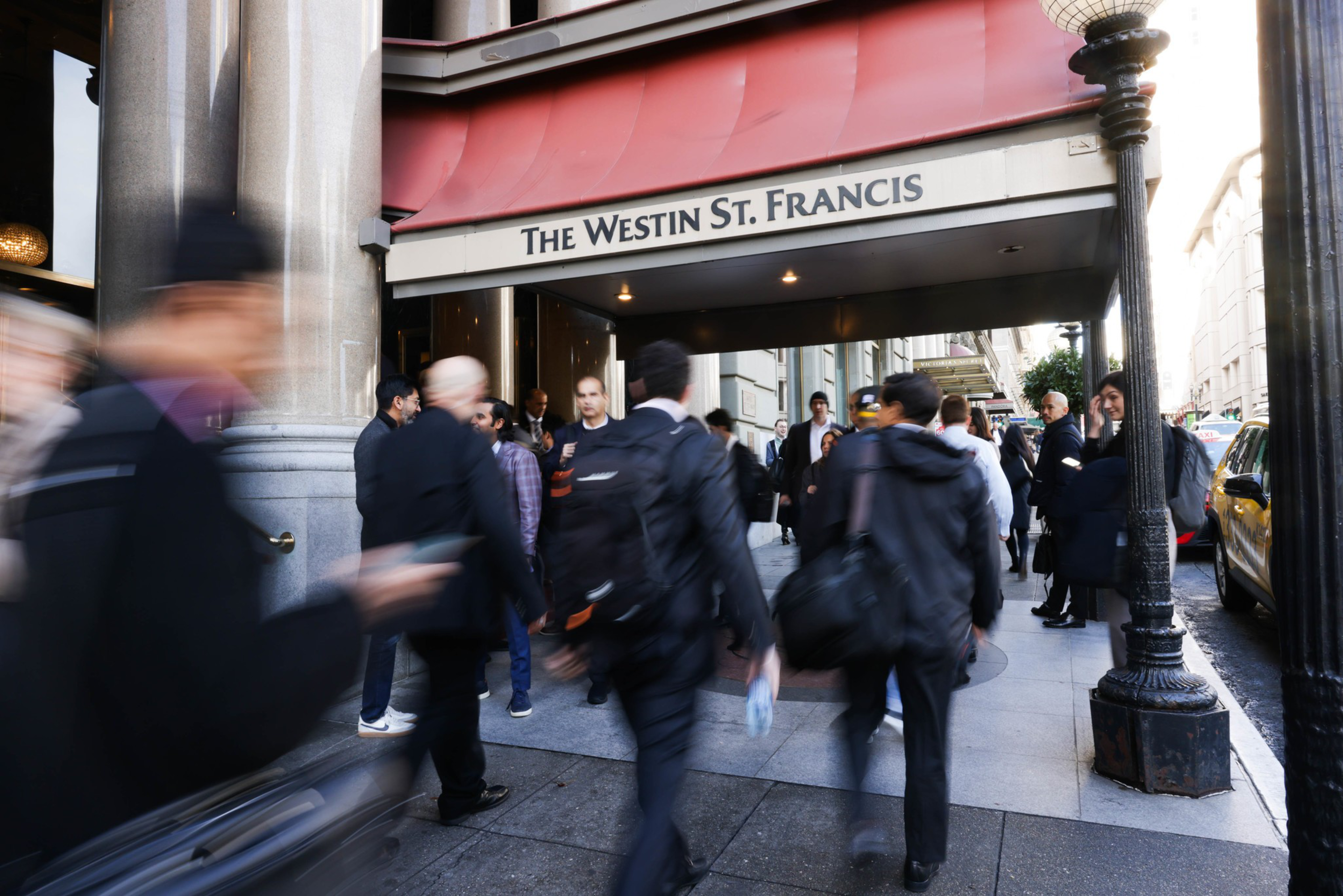 People wearing suits walk into a hotel.