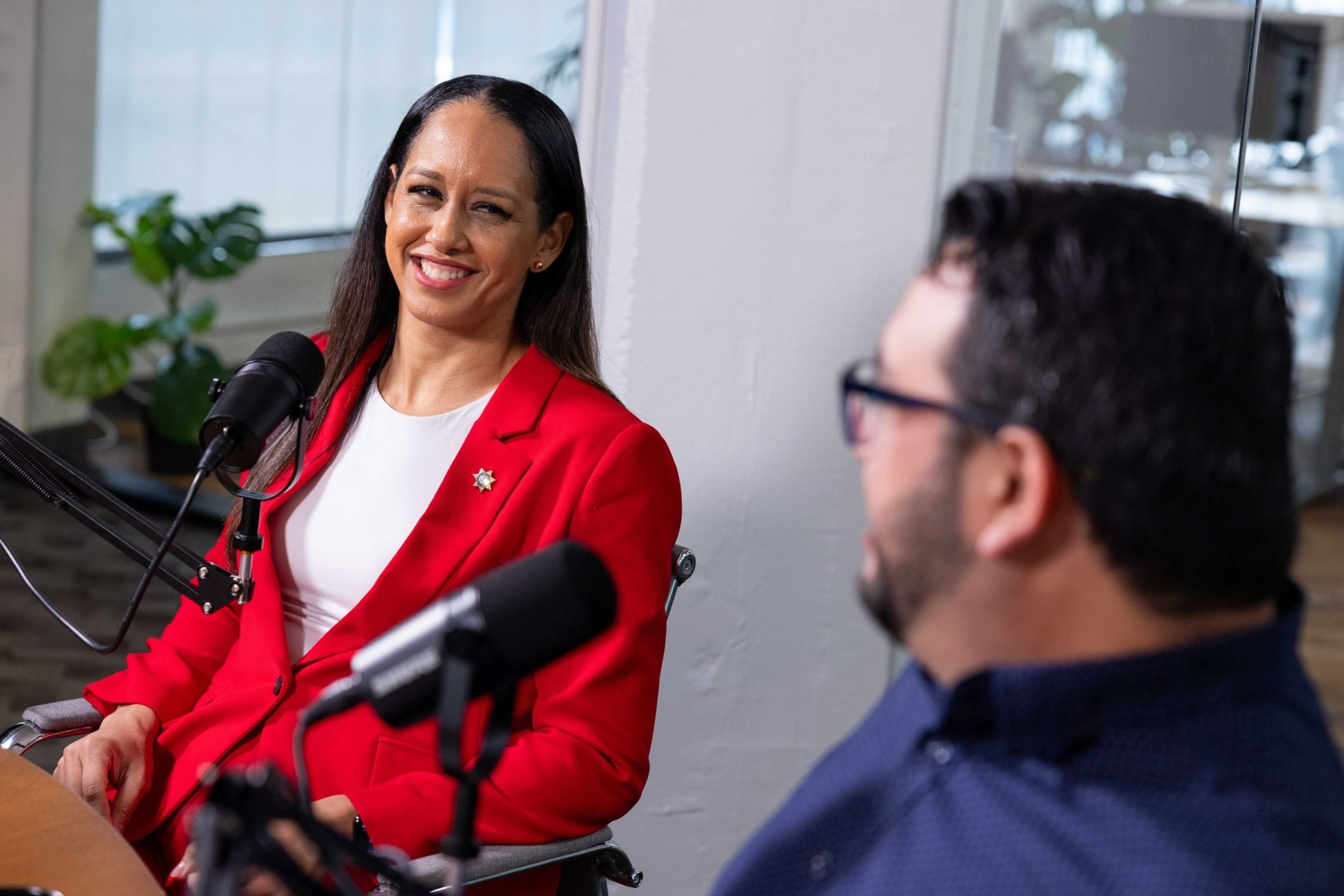 Two women are shown; one holds an open box containing a ceremonial key. Flags are visible in the background, and they both appear to be smiling.