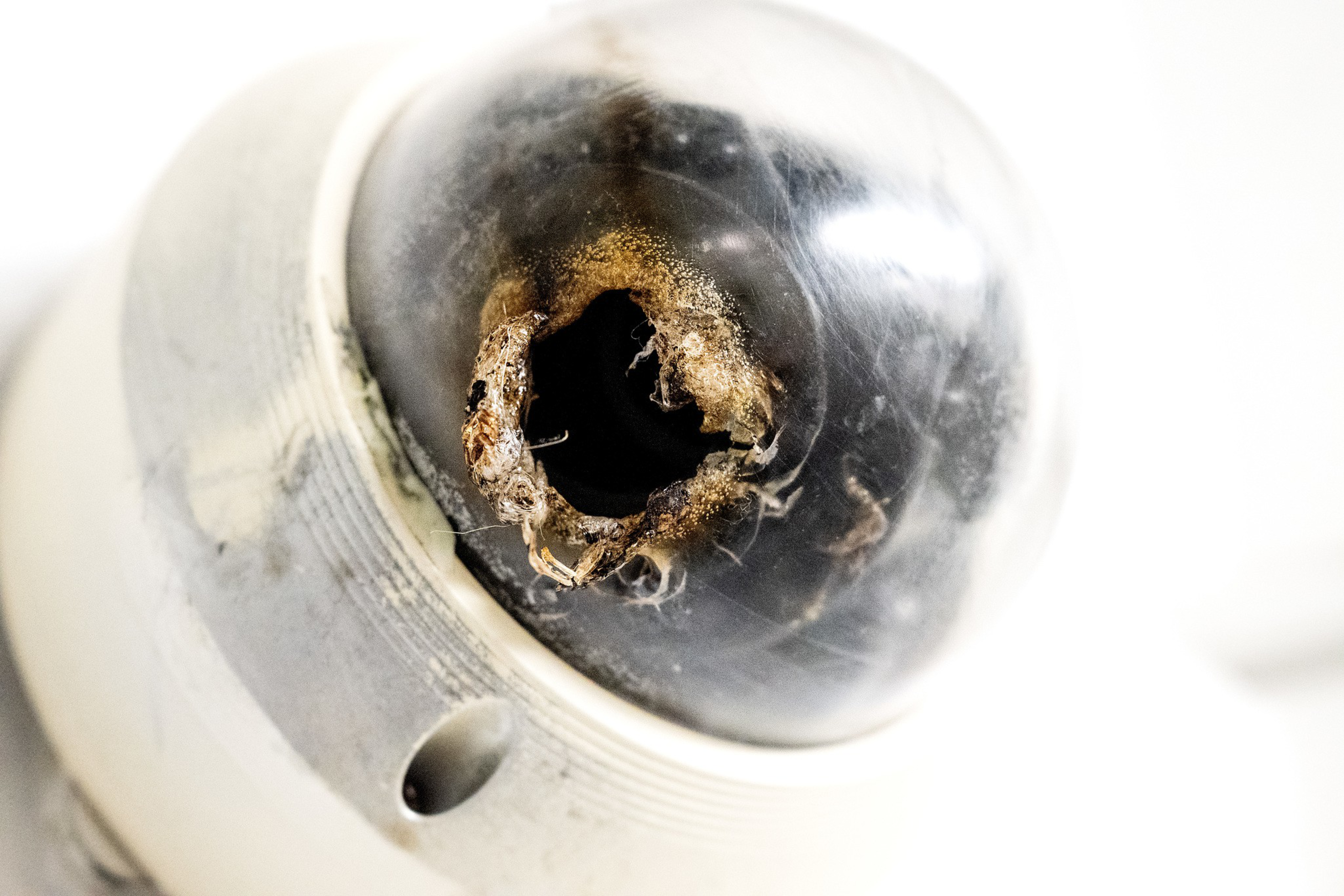 A close-up of a security camera shows its dome cracked and melted, with visible damage and cobwebs inside the broken area.