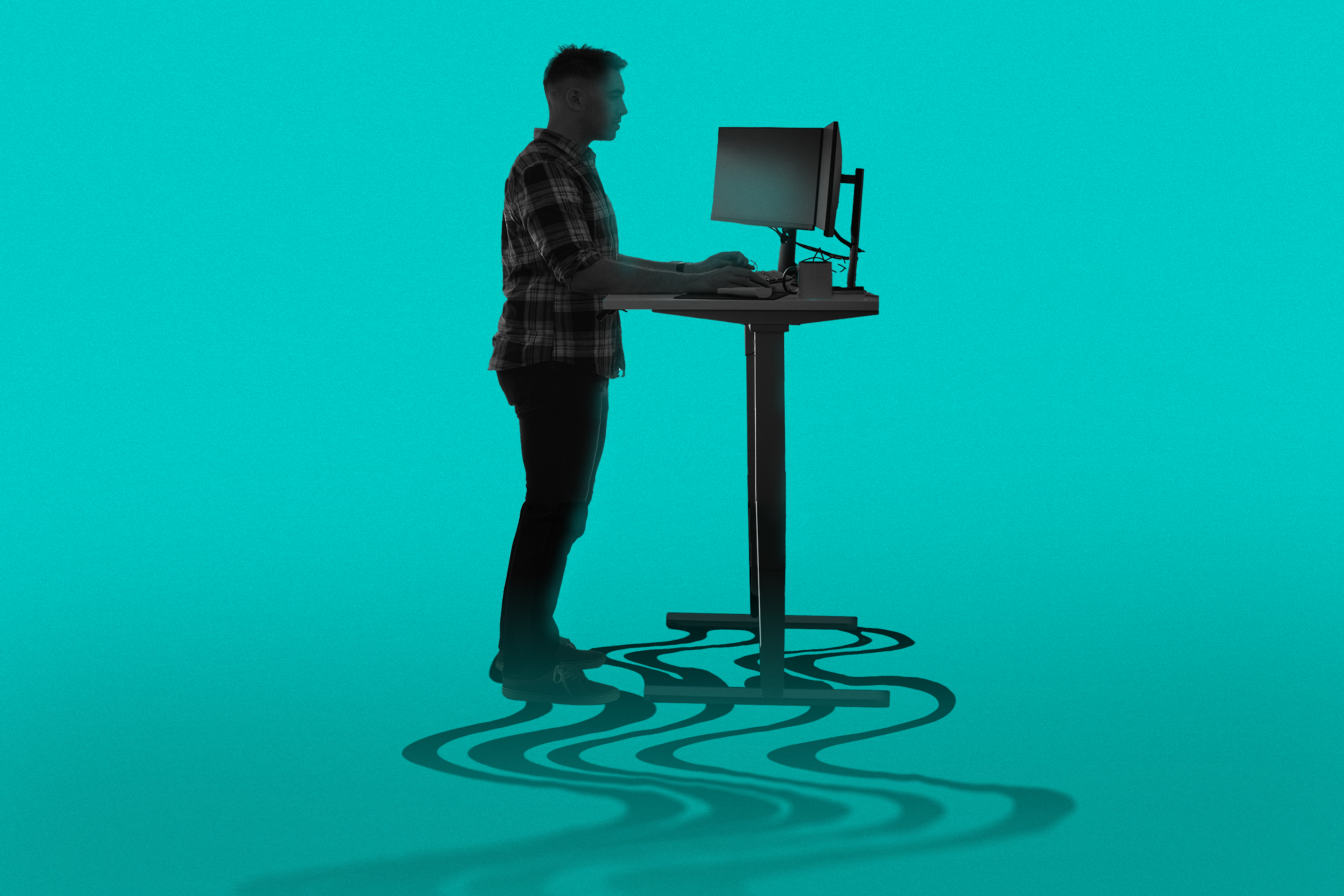 A person stands at a height-adjustable desk using a computer. Their shadow on the floor has a wavy pattern. The background is a solid teal color.