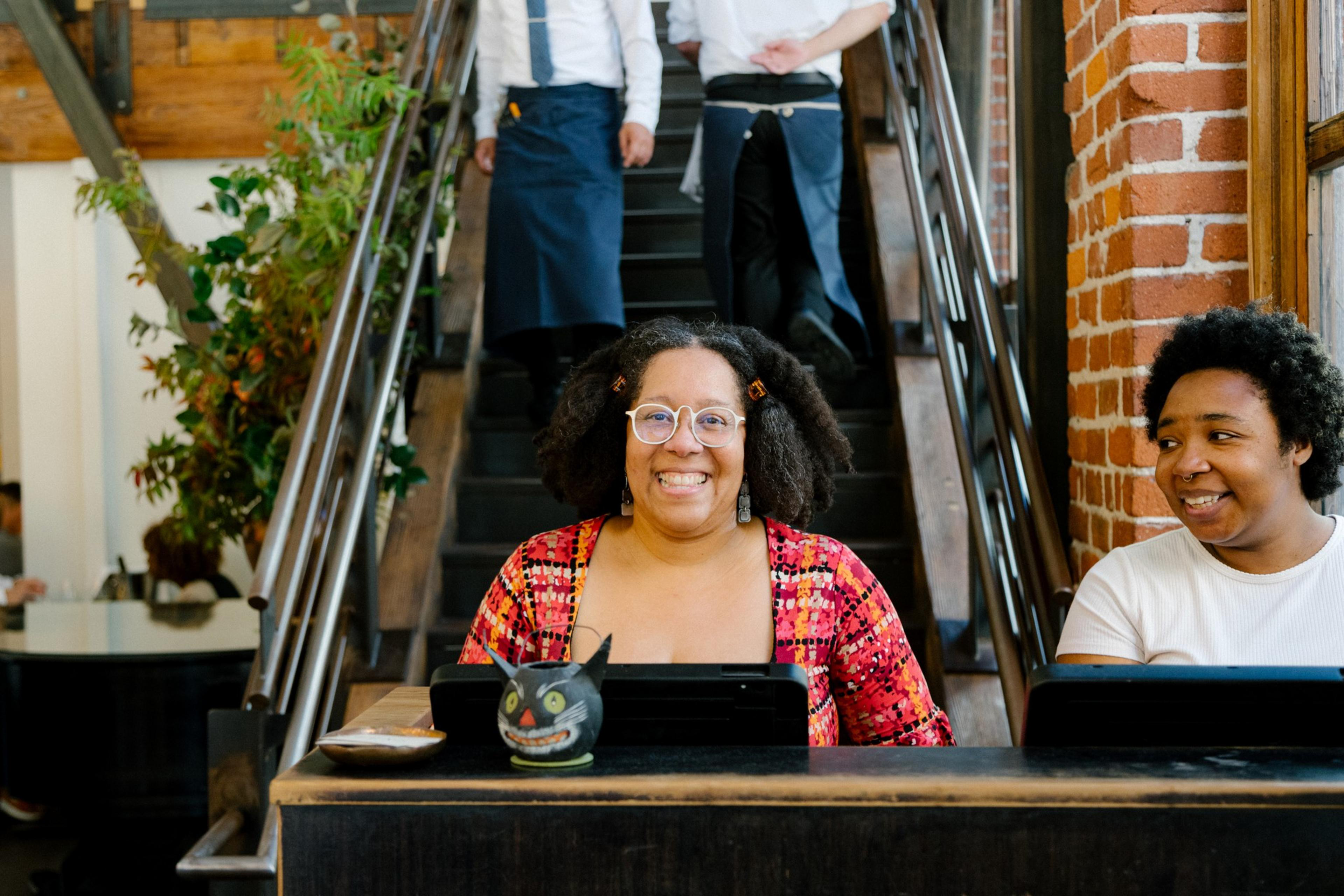 A hostess stands behind a counter while smiling.