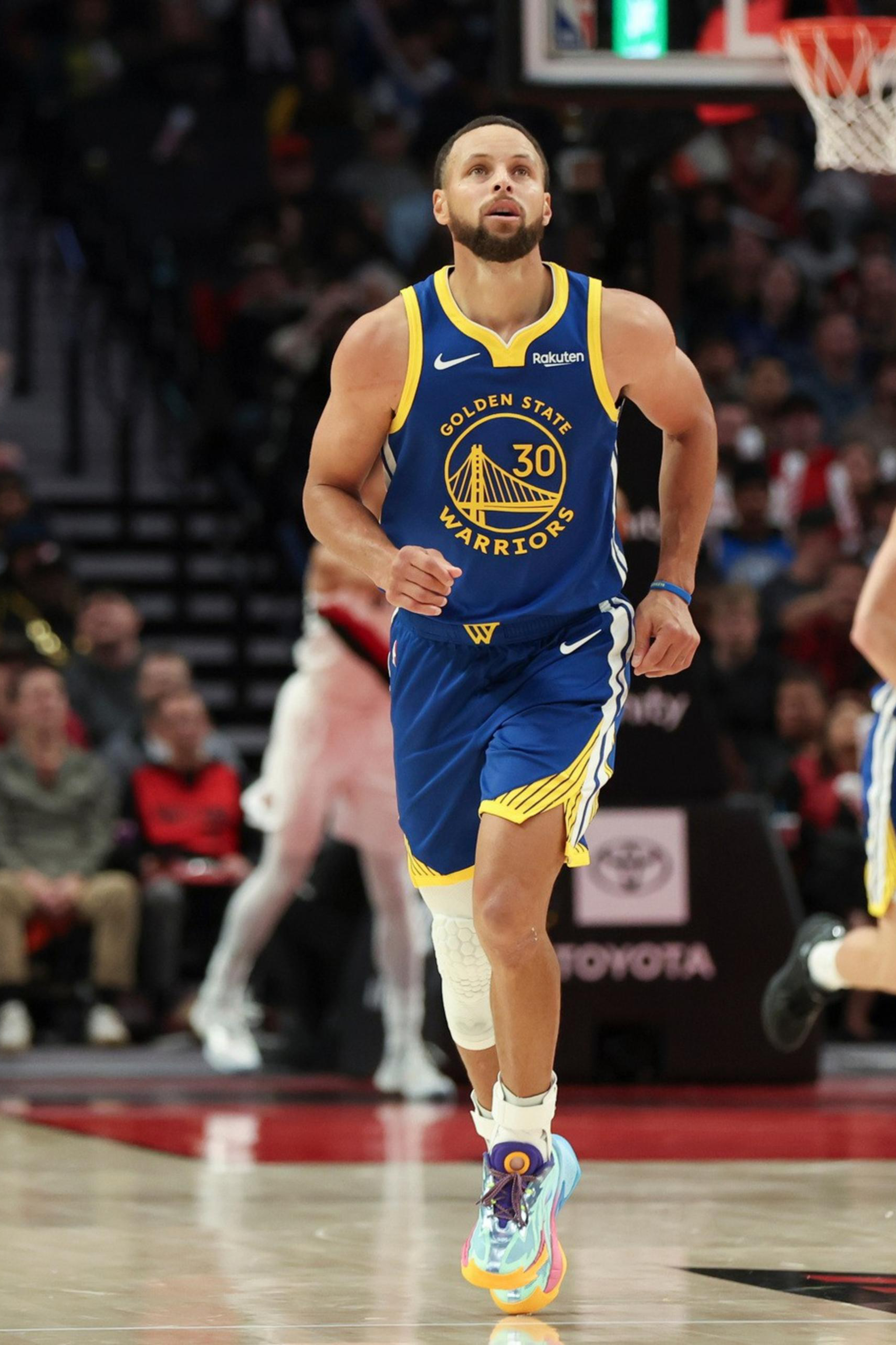 A Golden State Warriors player wearing jersey number 30 runs on the basketball court with a teammate and audience in the background.