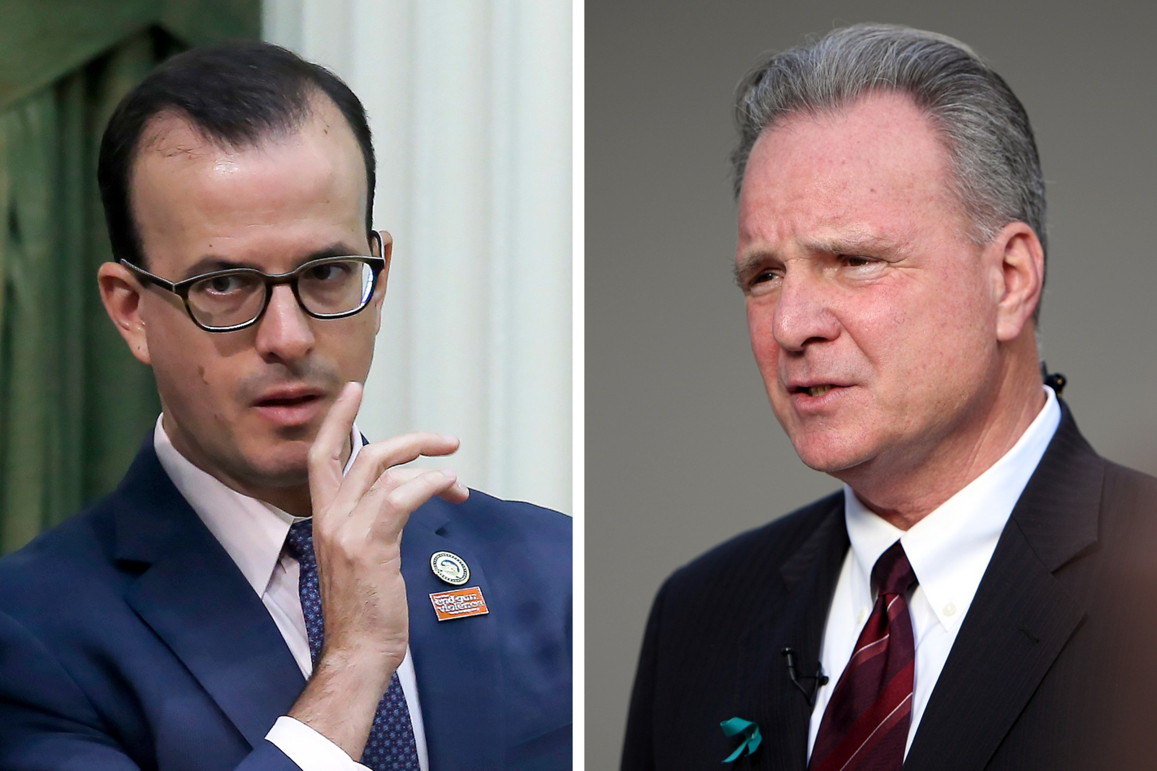 Two men in suits are shown side by side; the man on the left wears glasses and gestures with his hand, the man on the right looks serious with a pin on his lapel.