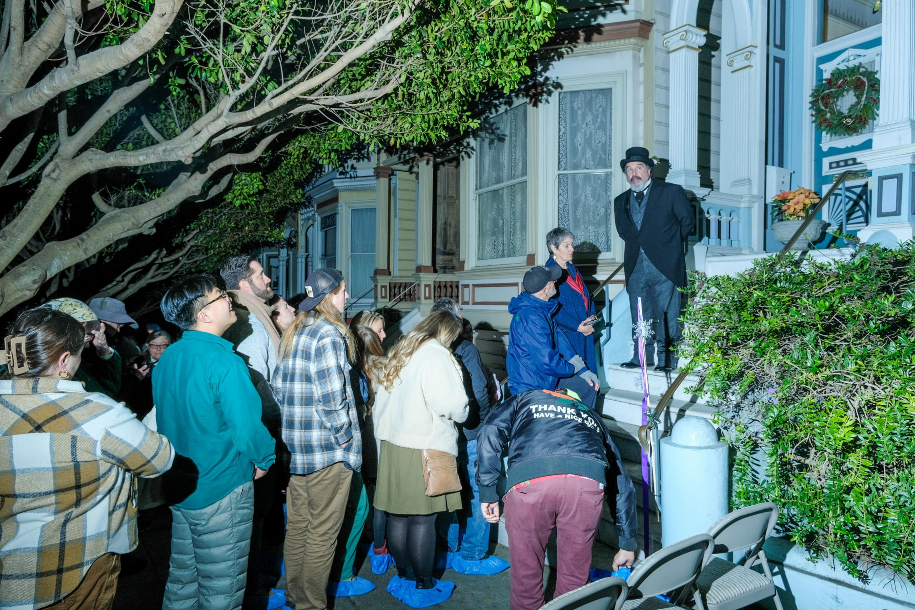 A line of people wait to get in an old victorian house.