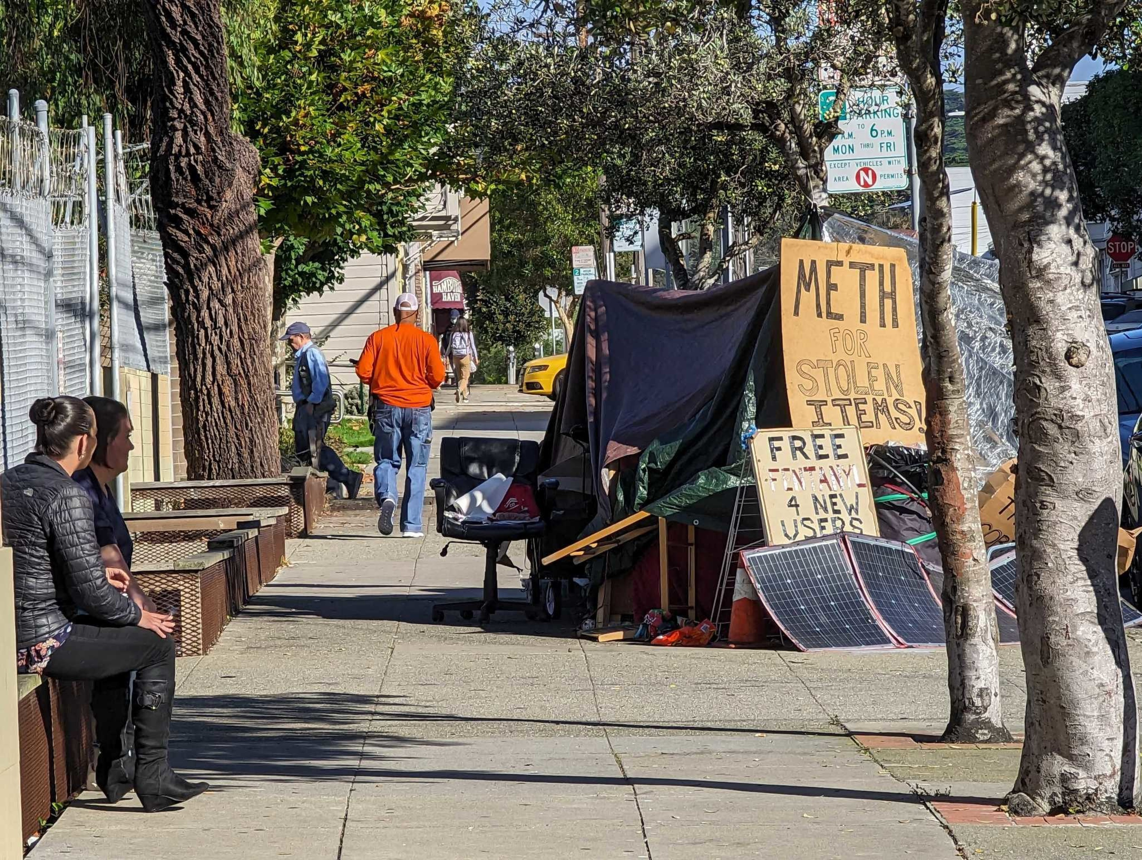 Signs reading "Meth for stolen items" and "free fentanyl for new users" sit atop Joseph Adam Moore's encampment on Ninth Avenue north of Geary Boulevard in San Francisco's Inner Richmond neighborhood.