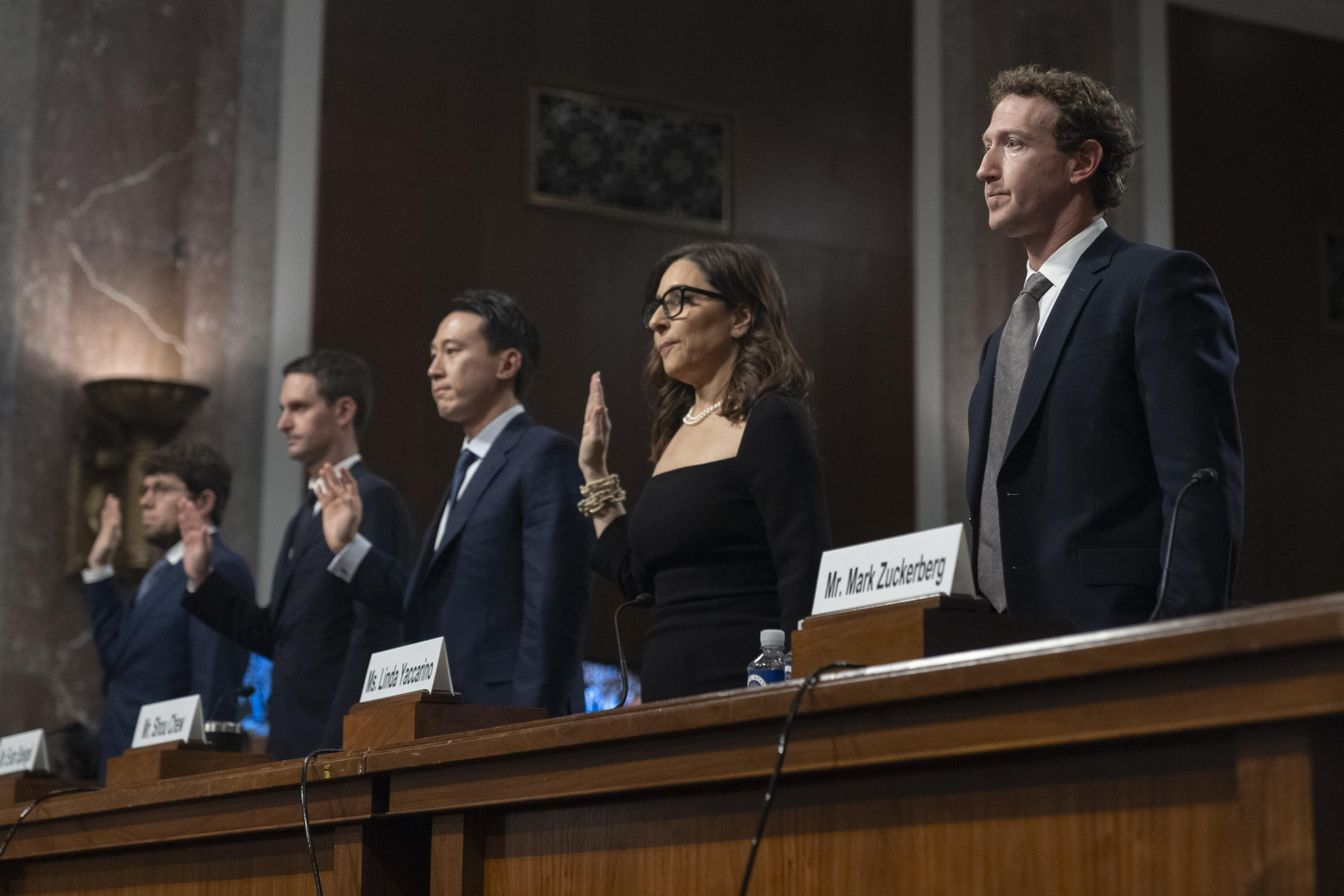 Four men and one woman stand and raise a hand