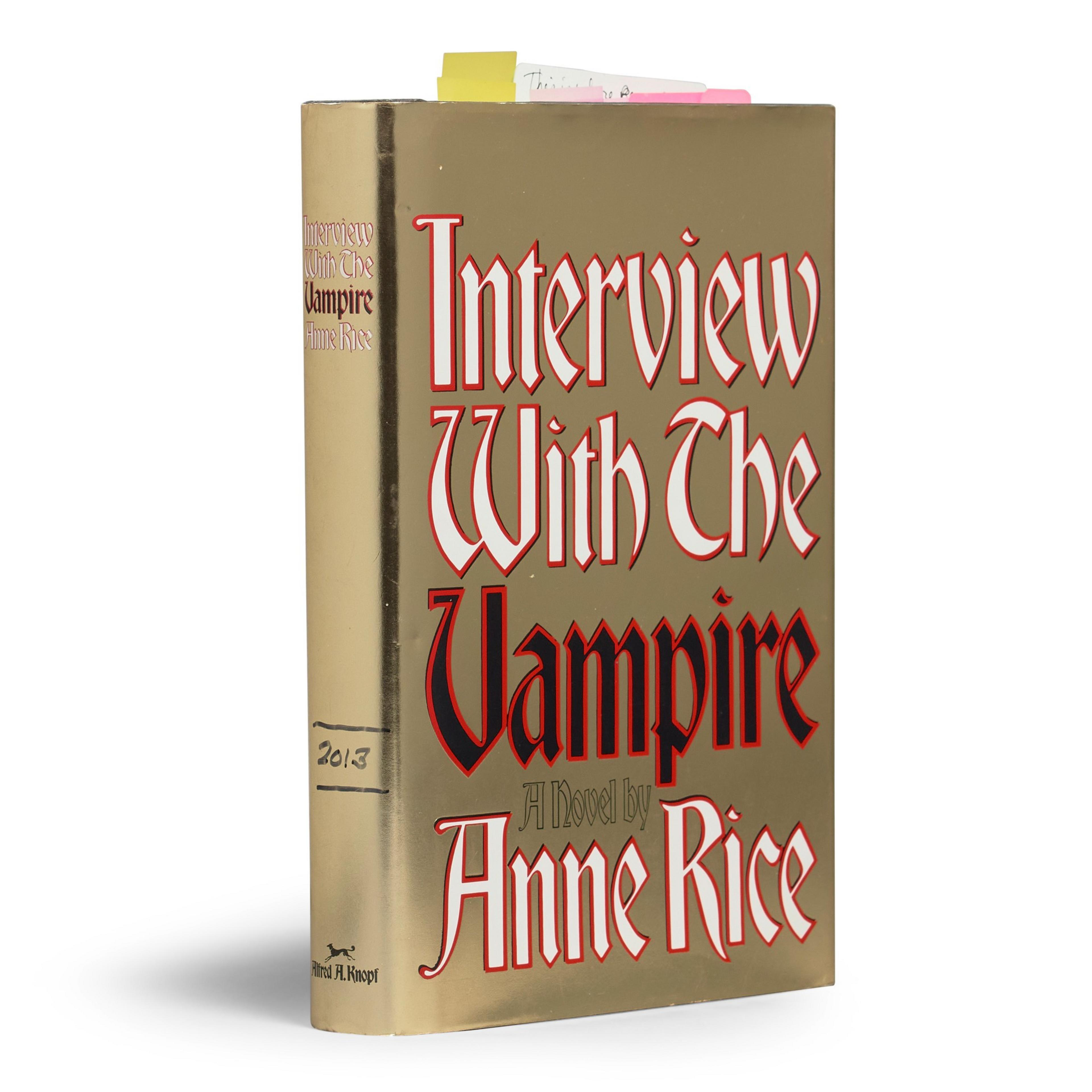 The image shows the book &quot;Interview With The Vampire&quot; by Anne Rice, with a gold cover and red and white text. Sticky notes protrude from the top.