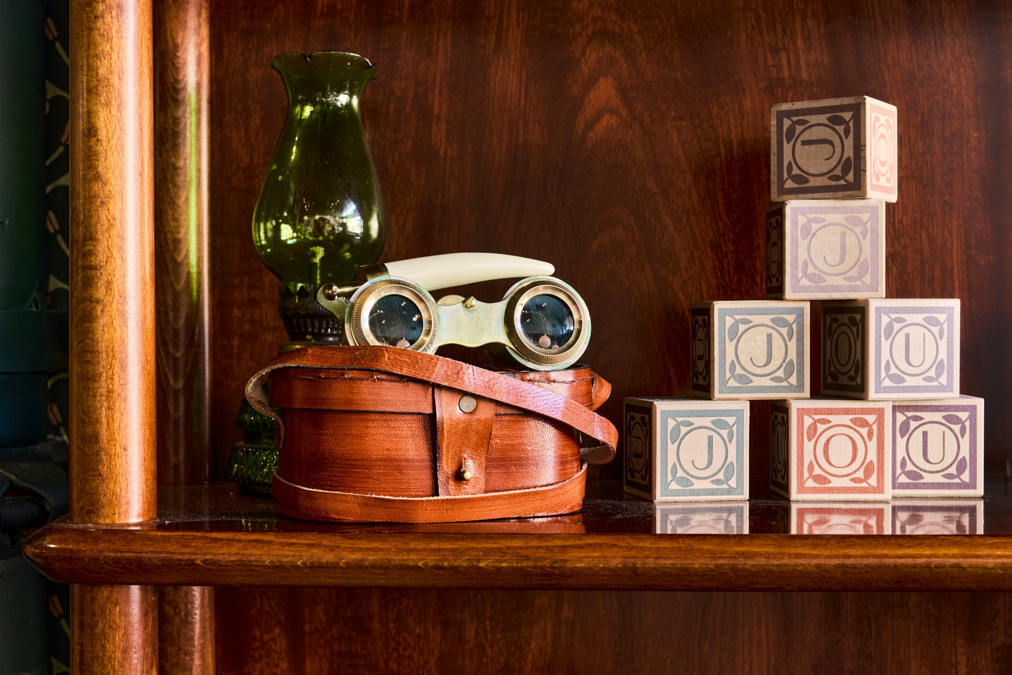 A green glass lamp, vintage opera glasses with ivory handles on a ...