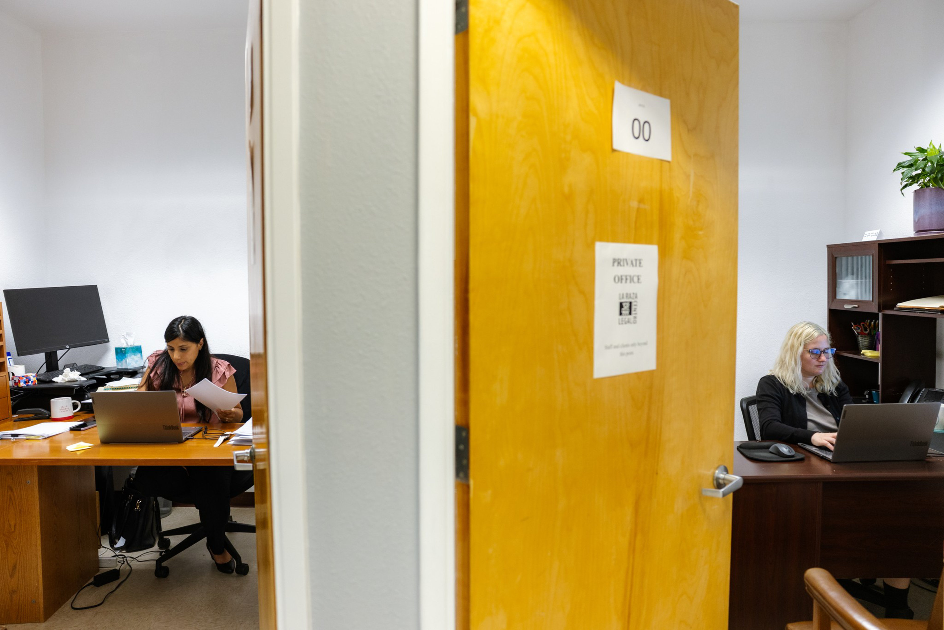 Two women work separately at desks in adjacent offices divided by an open door labeled “00" and ”Private Office.”