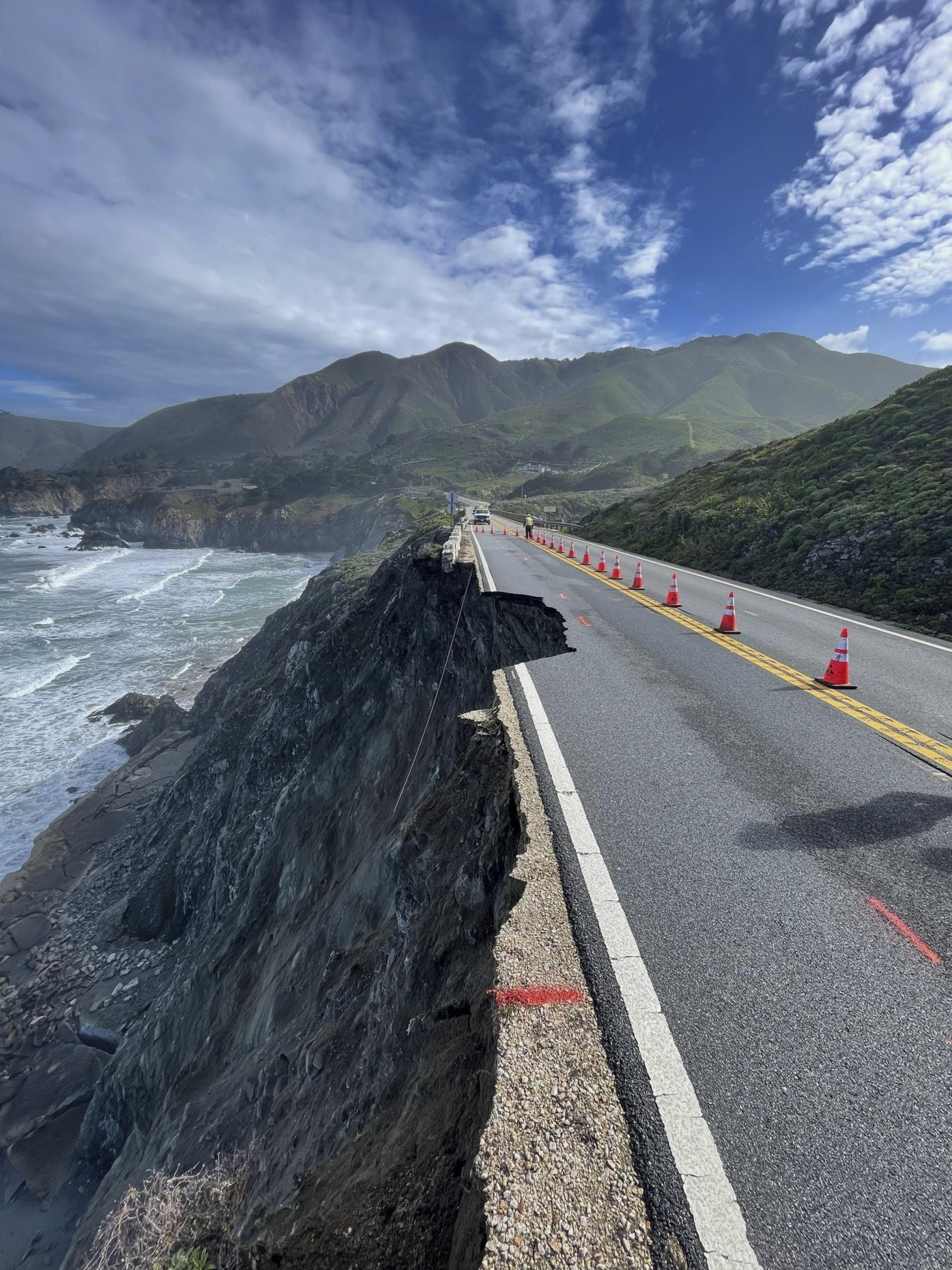 a long shot of a coastal, cliffside highway showing a section of road eroded away