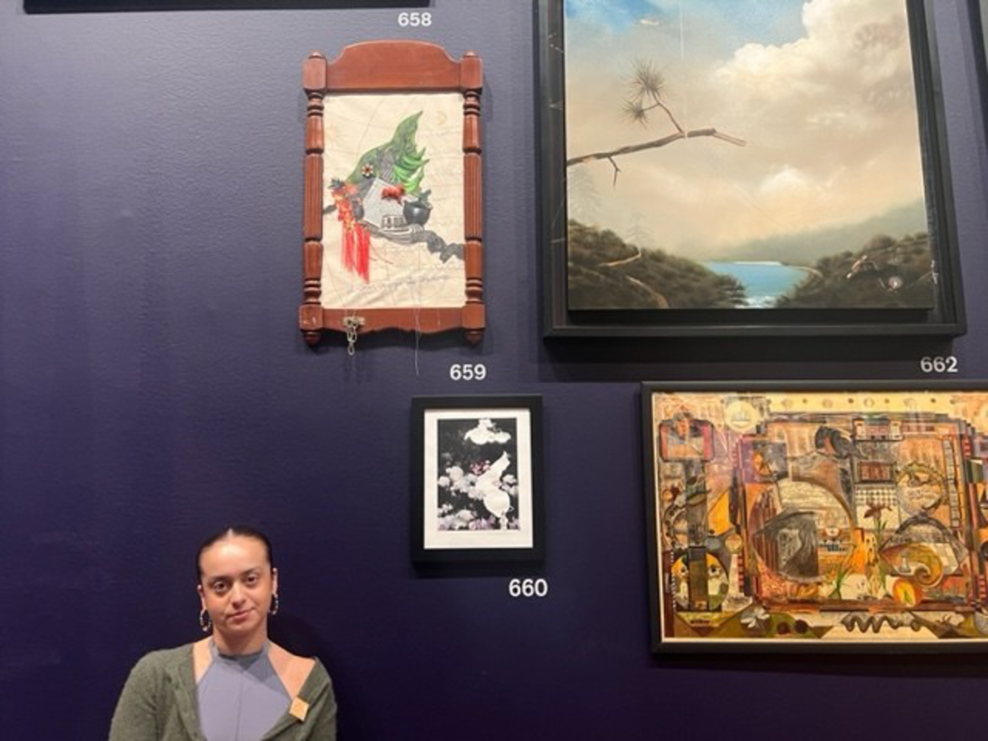 A woman stands in front of a dark purple wall displaying five framed artworks, each labeled with a number above or below them.