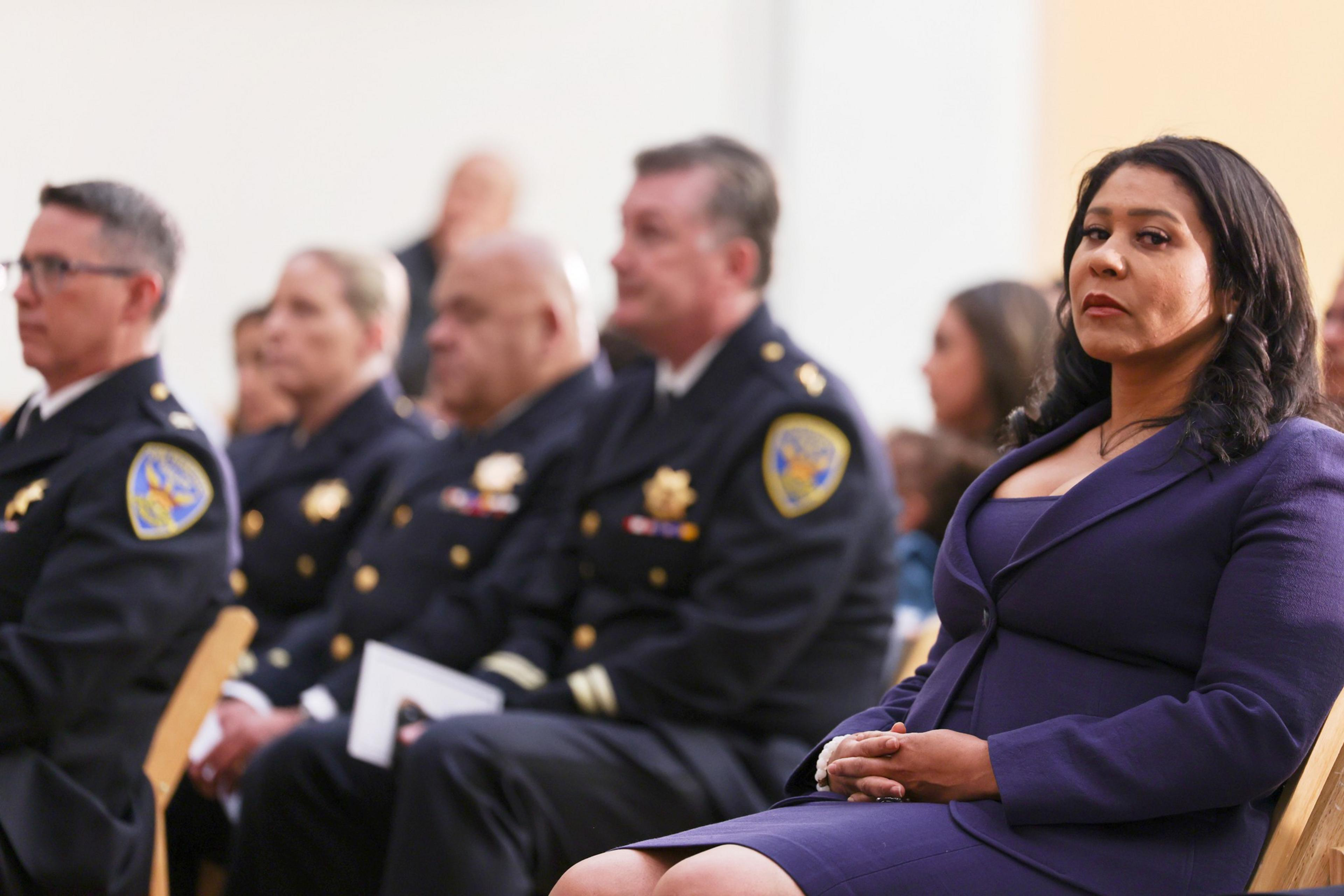 A woman sits next to a row of police officers.