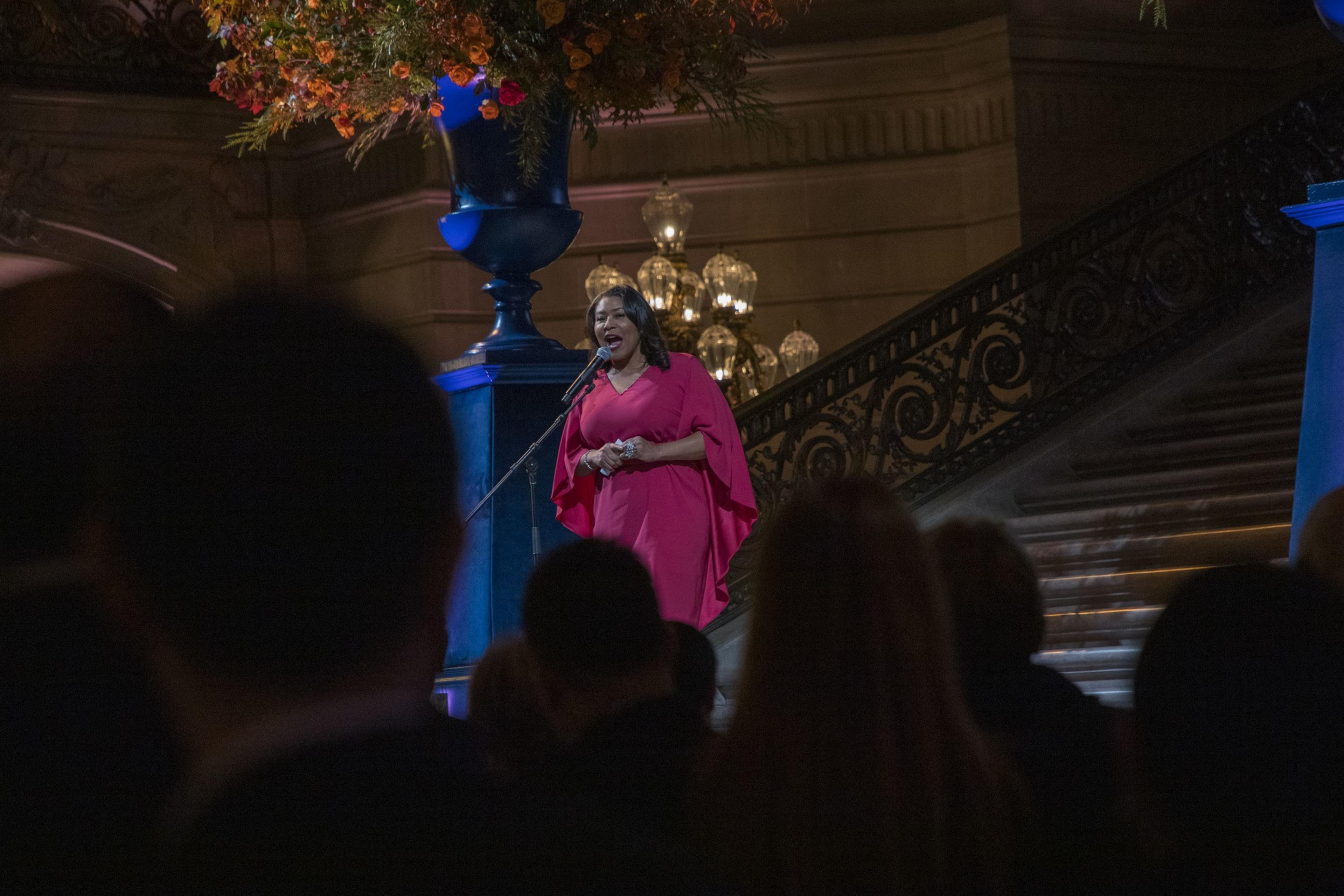 Mayor London Breed welcomes guest inside San Francisco City Hall in a red dress.