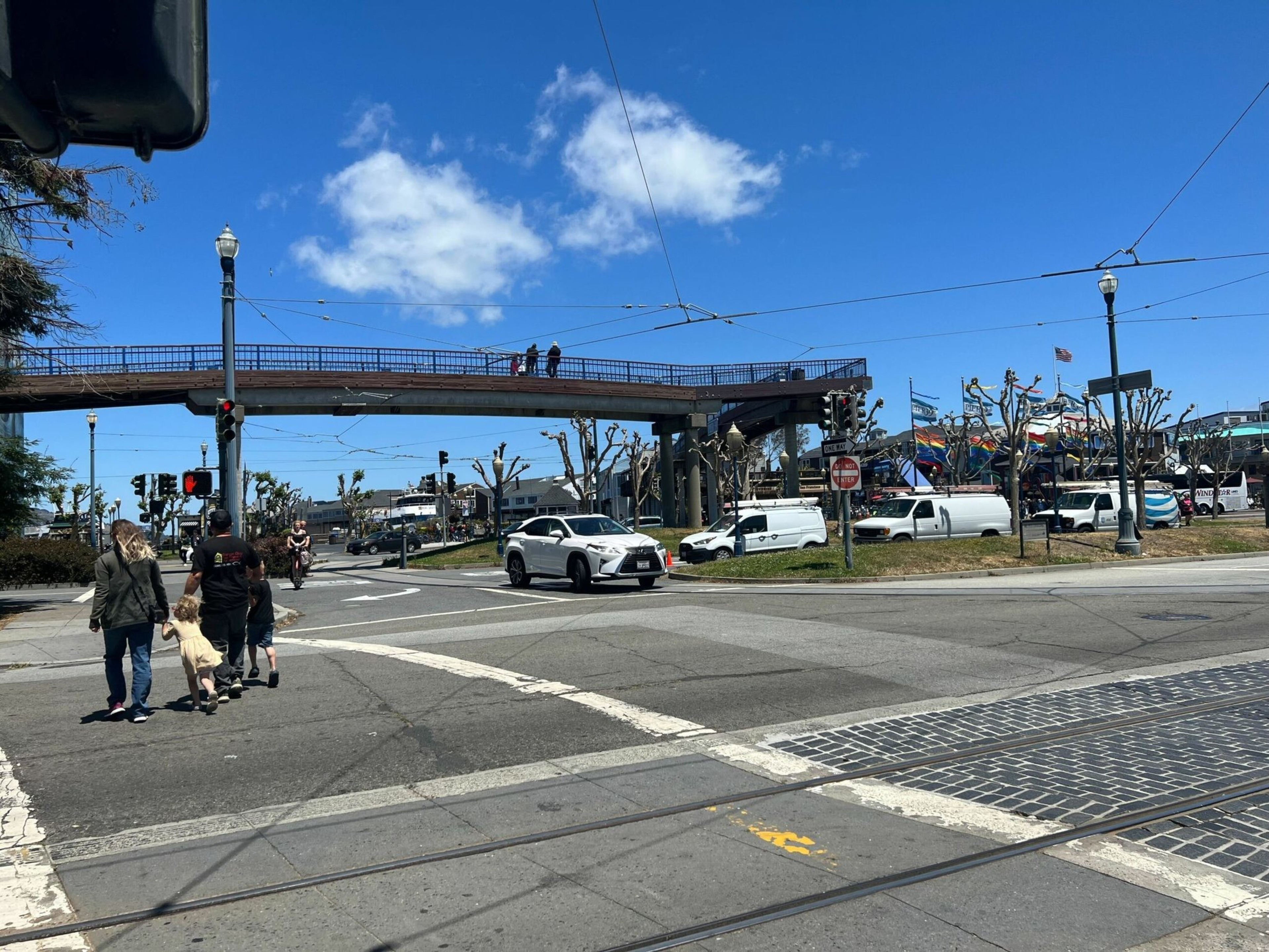 Pedestrians and motorists move along Embarcadero on Monday, near the scene of a car-to-car shooting that injured six on Father's Day. | Julie Zigoris/The Standard