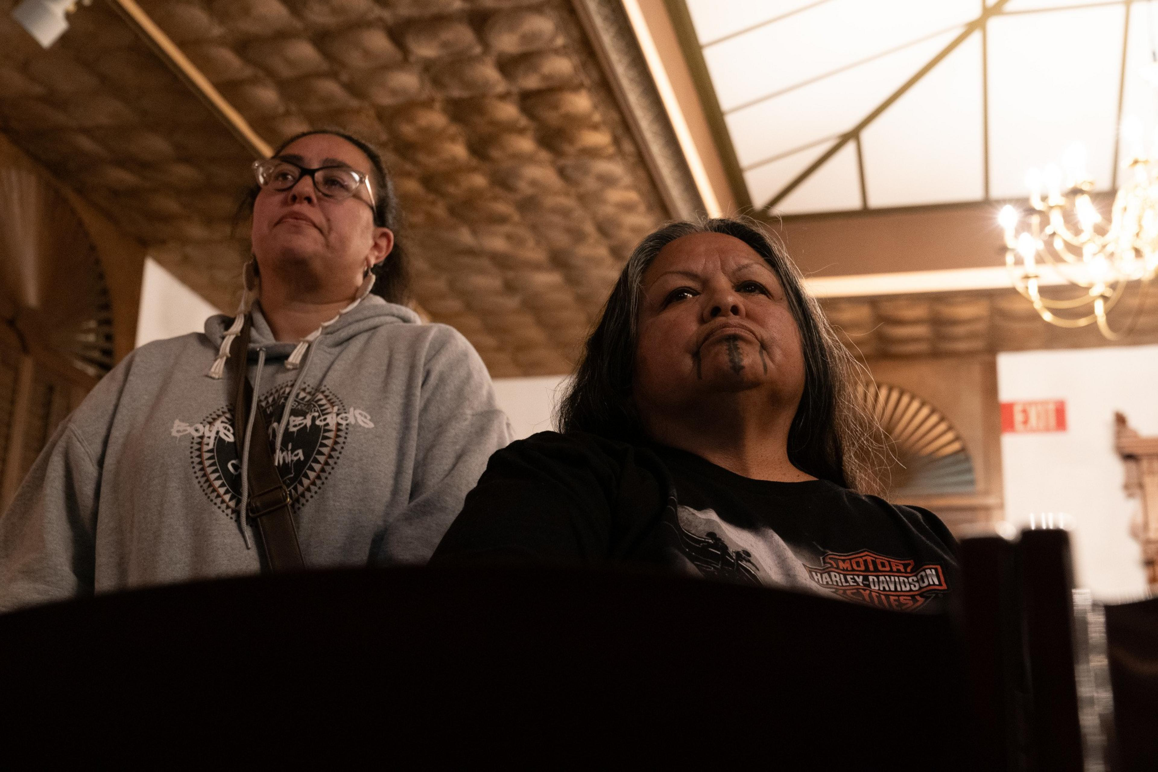 Two people sit and listen to a speaker.