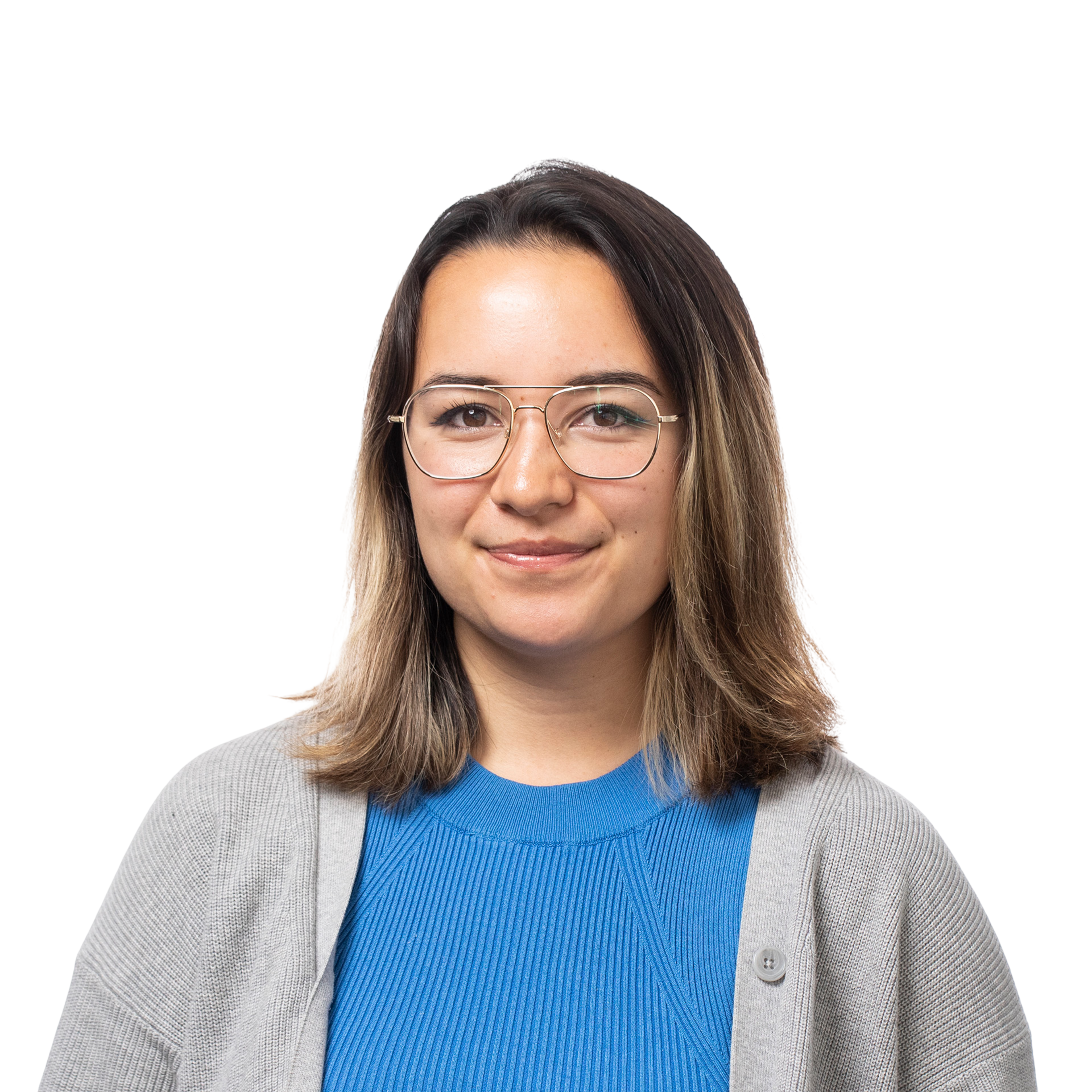 A young woman with shoulder-length brown hair wears clear-framed glasses, a bright blue ribbed sweater, and a light gray cardigan, smiling softly.