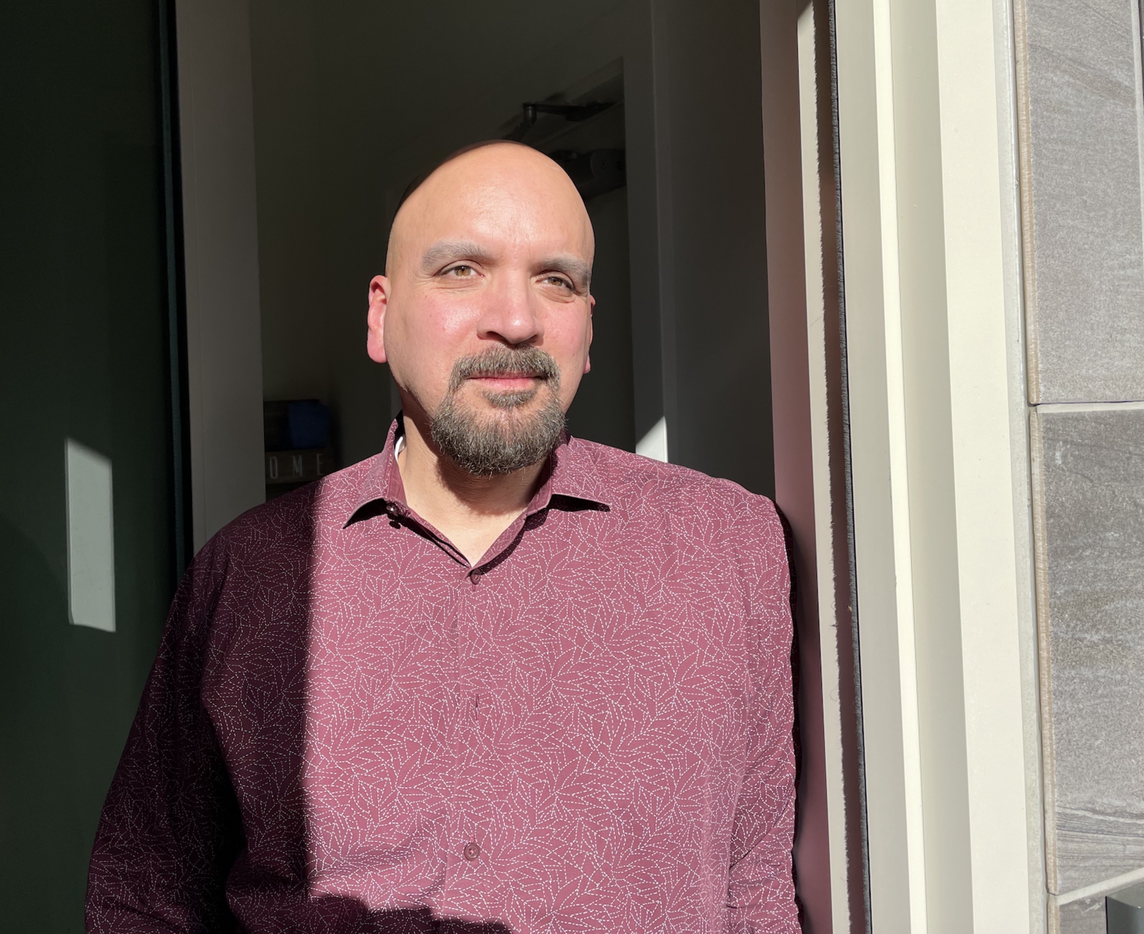A man stands in his home doorway.