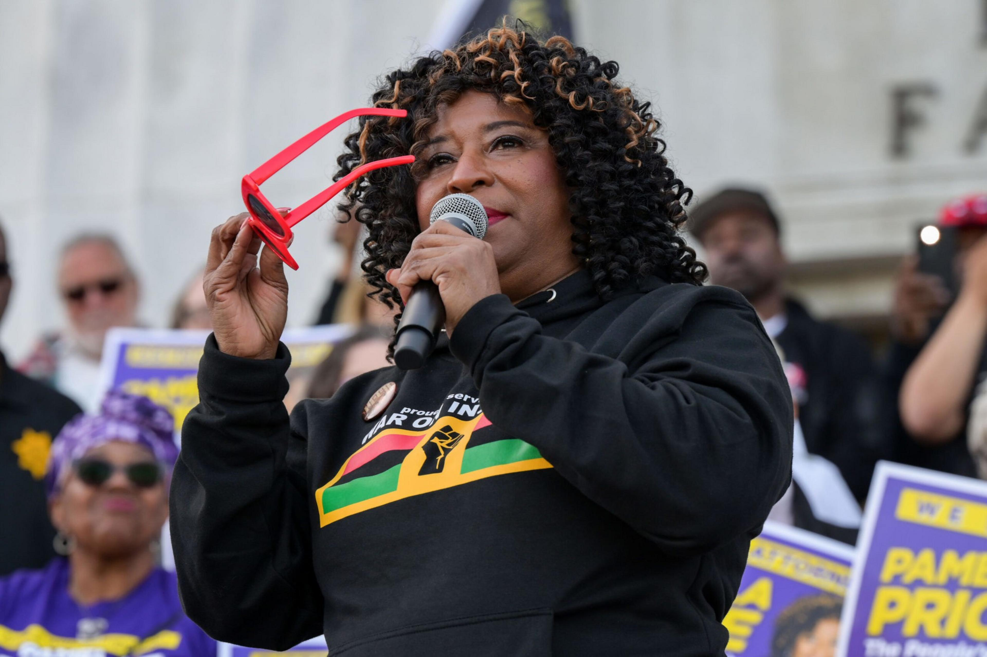 A woman stands holding a microphone.