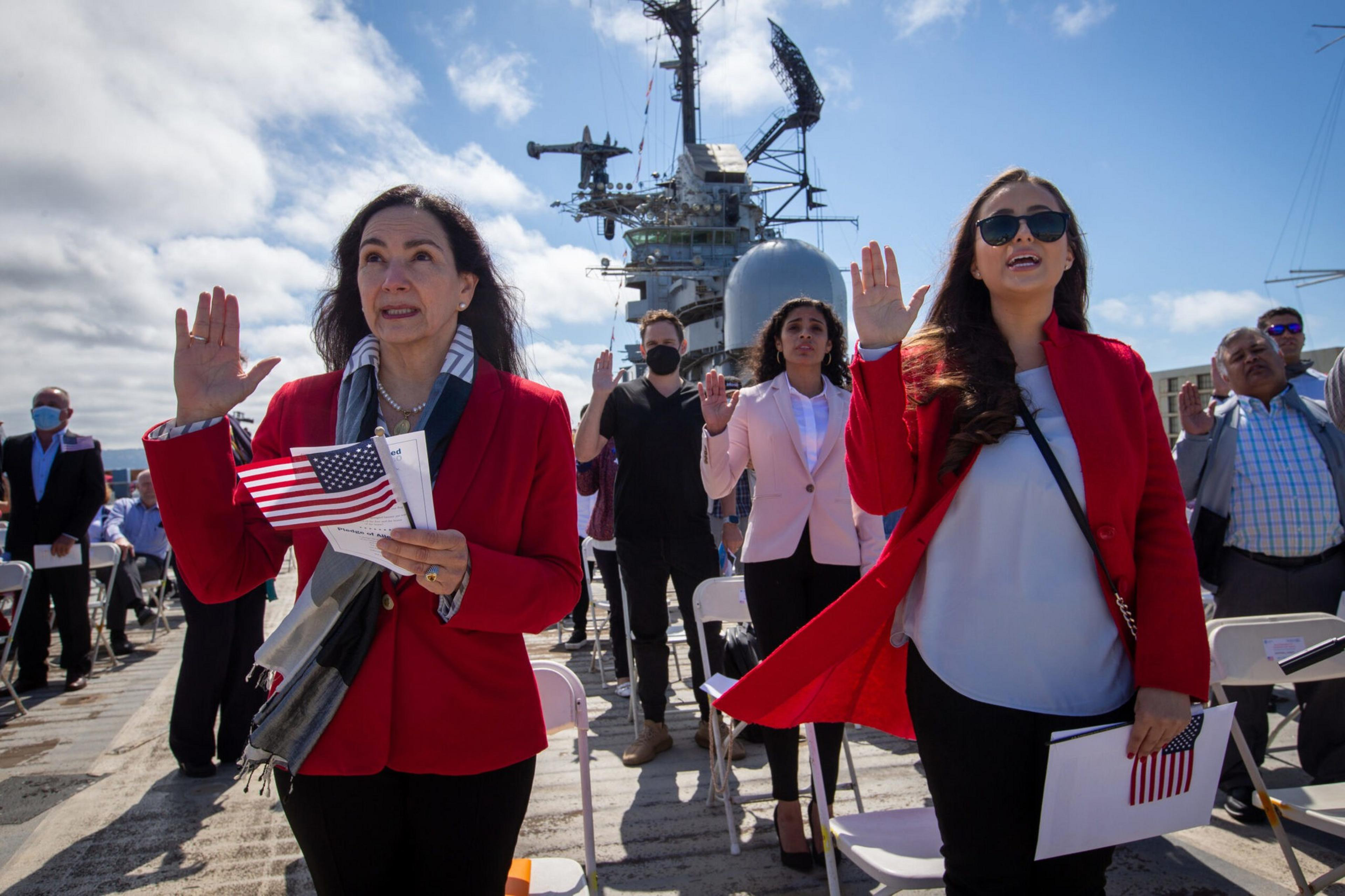 Maria Laura Limpias Chavez, left, of Bolivia, Sahara Loffsner, of Colombia, and fellow new American citizens, take the Oath of Allegiance during a naturalization ceremony on the flight deck of the USS Hornet Museum in Alameda in July 2021. | Ray Chavez/Med