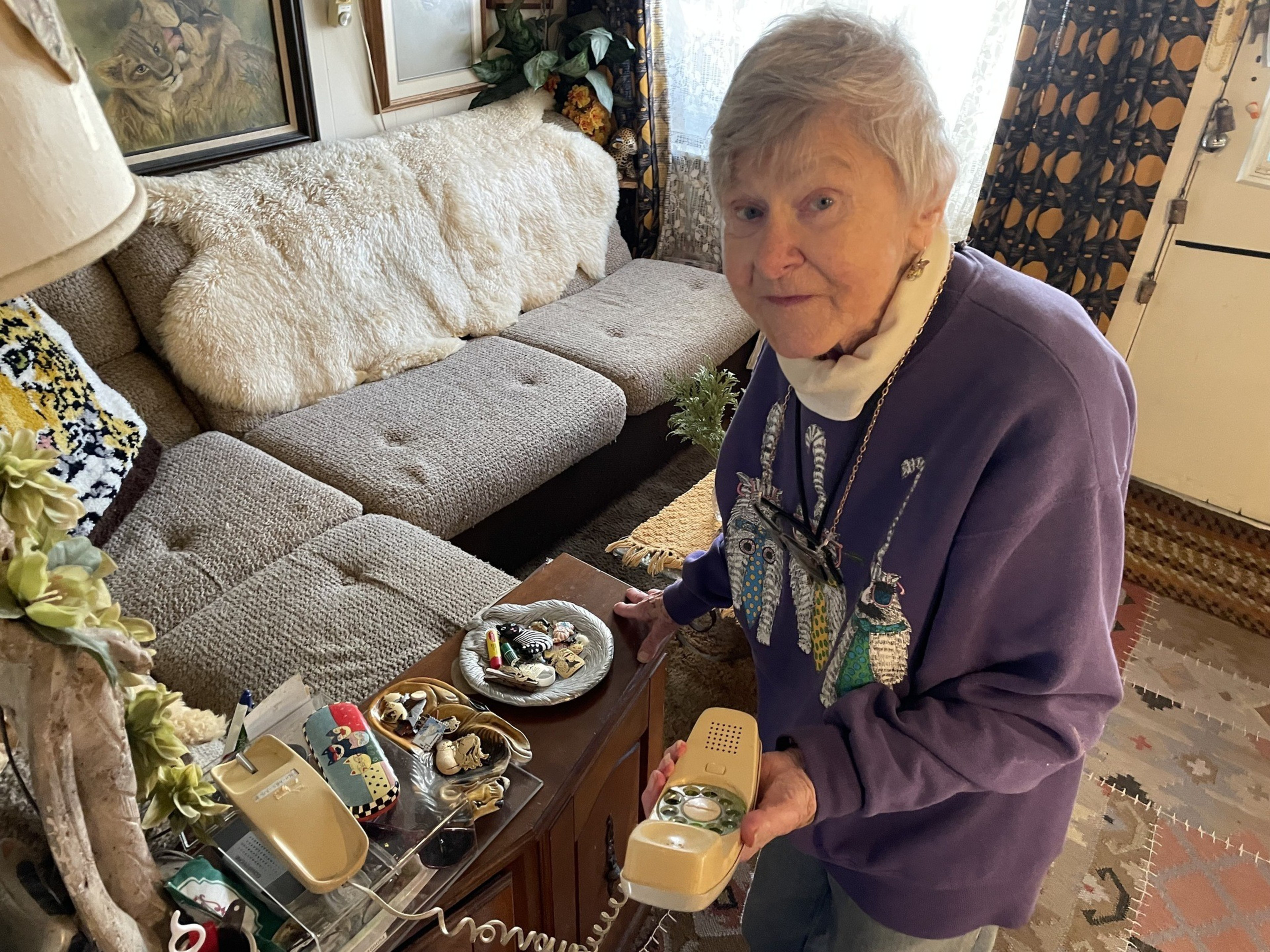 An old woman holds a landline phone.