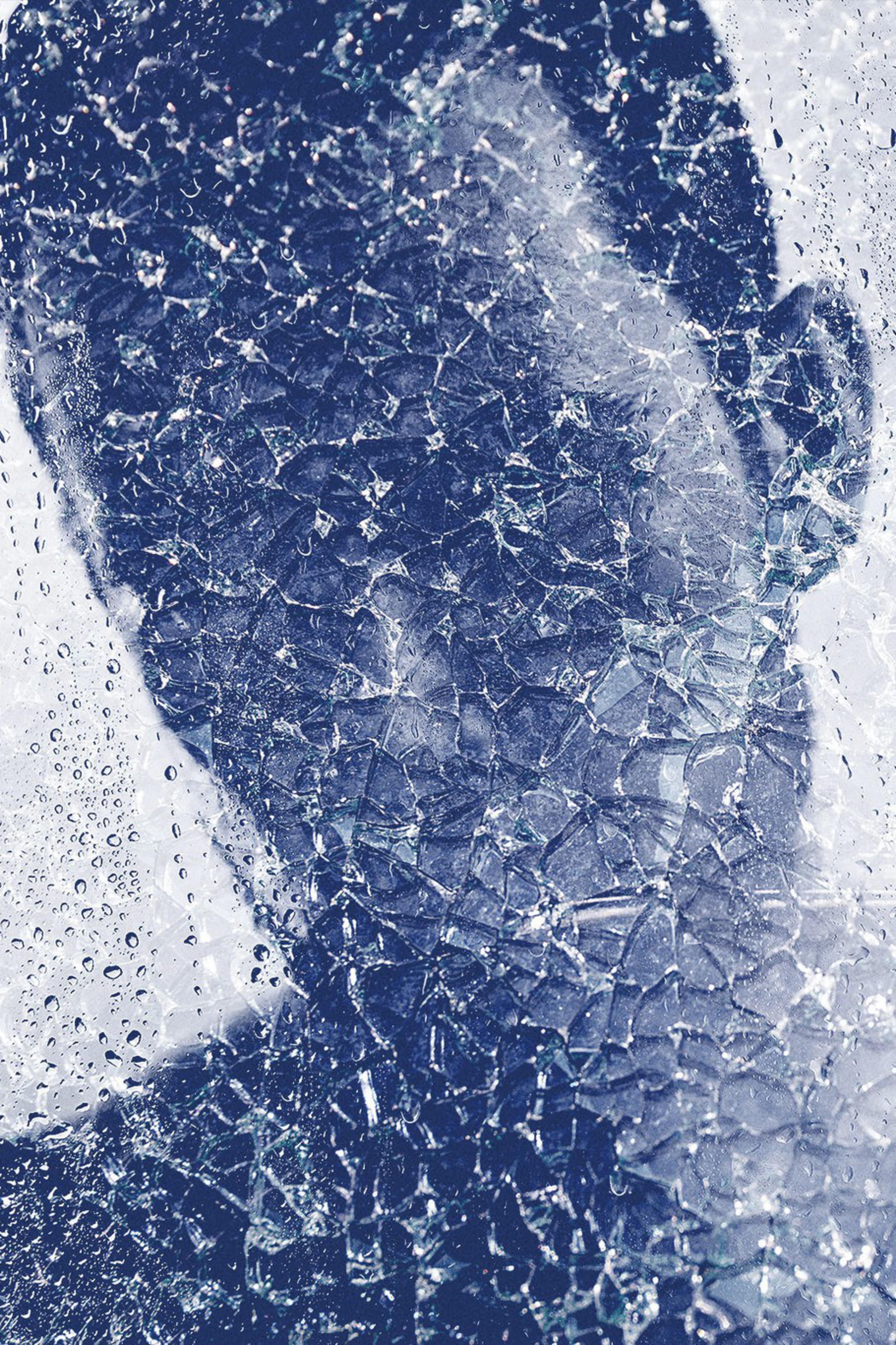 A person's silhouette appears blurred behind cracked glass with water droplets, creating a fragmented and abstract effect.