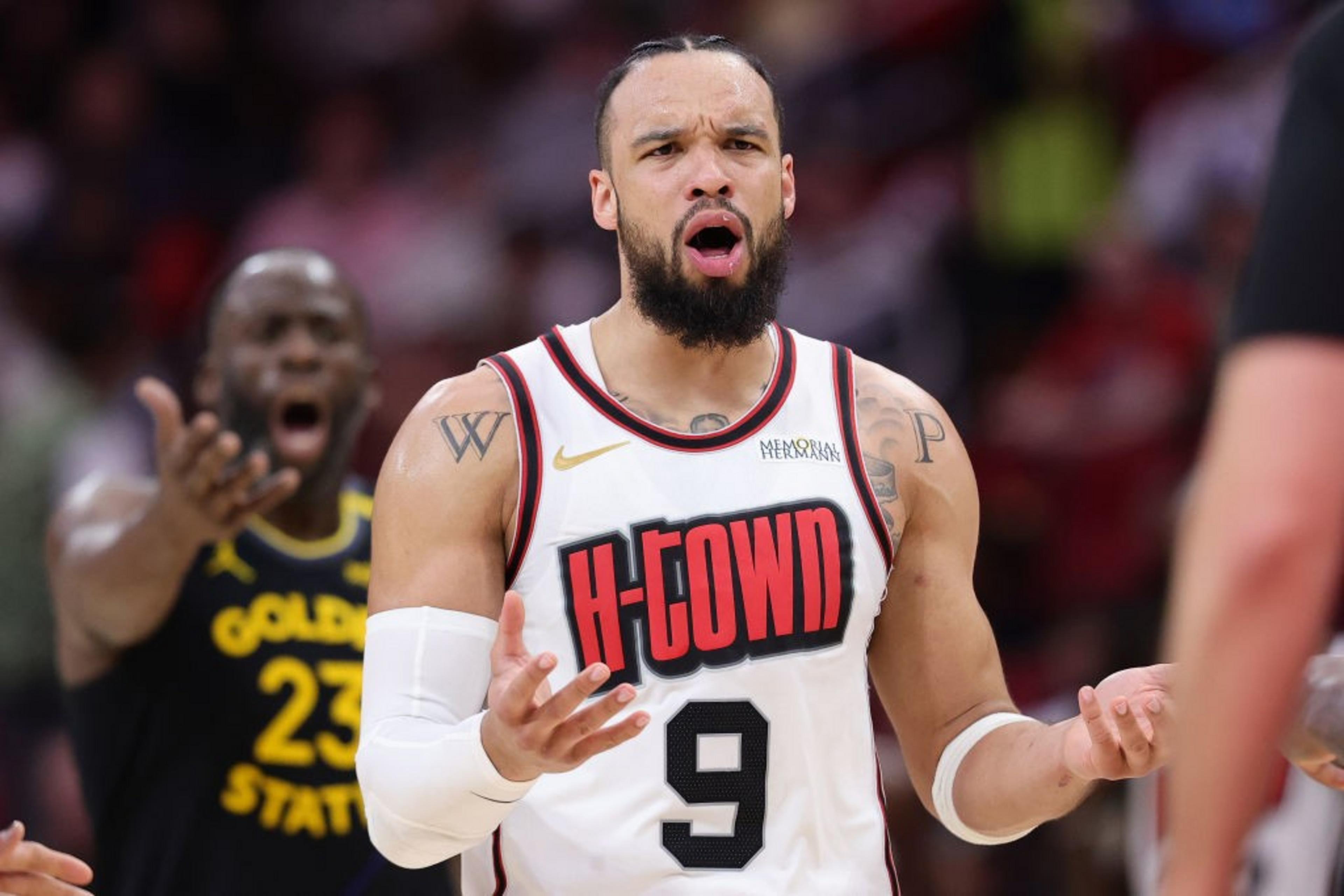 A basketball player in a white &quot;H-TOWN&quot; jersey stands with a surprised expression, arms outstretched. A player in a black jersey is shouting in the background.