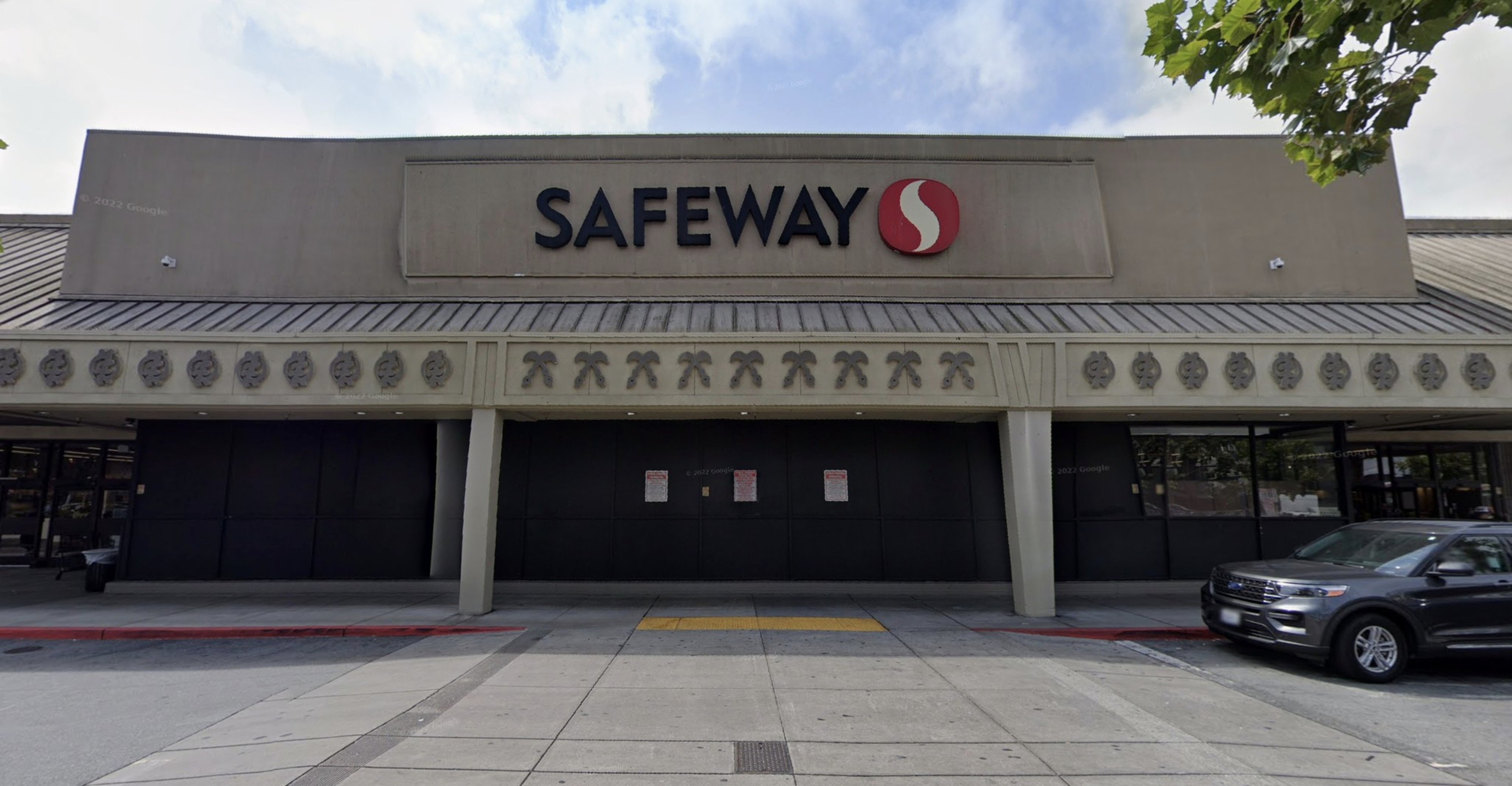 A exterior of a Safeway with cars to the right.
