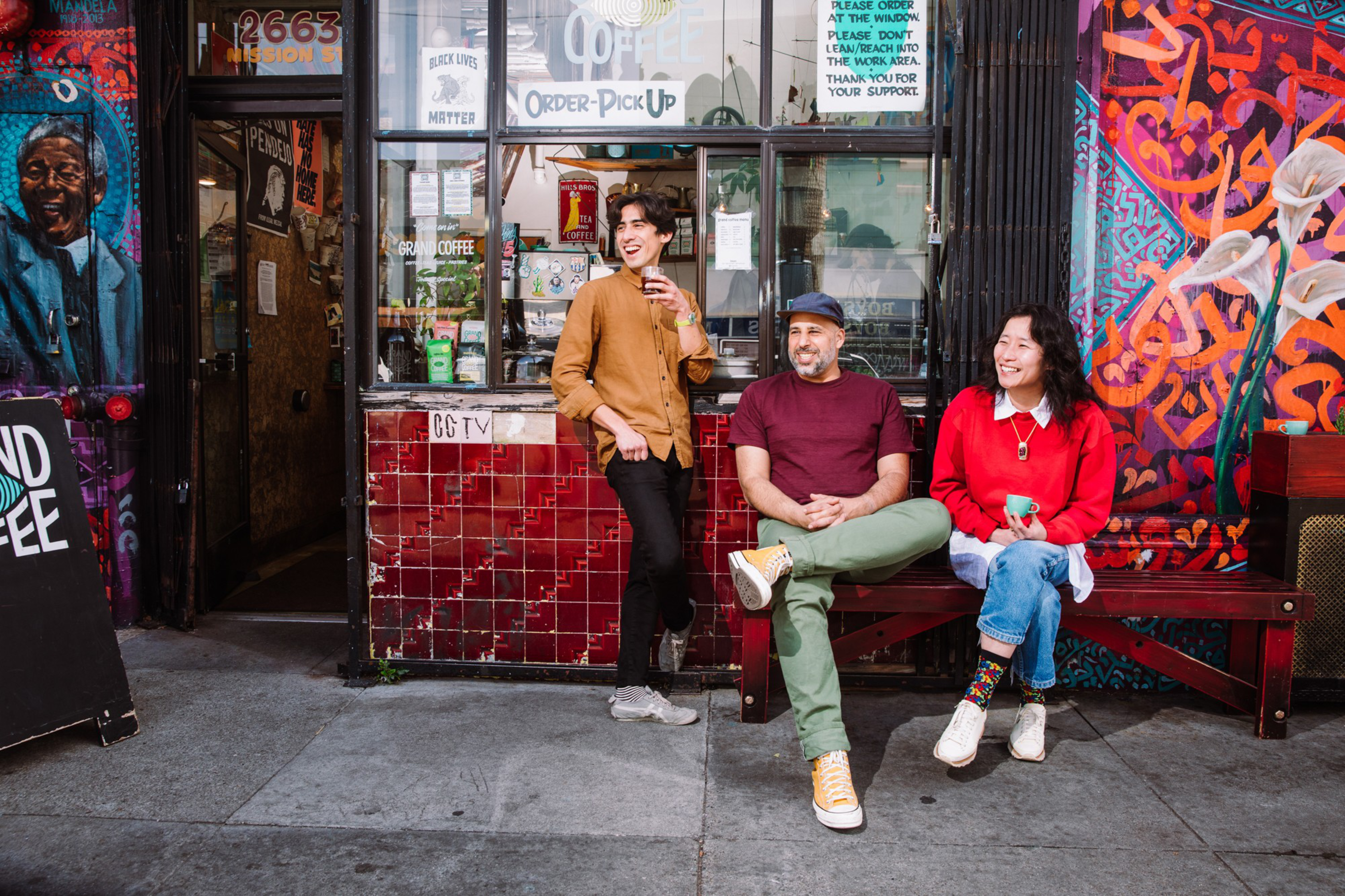 Three people pose in front of a coffee shop. 