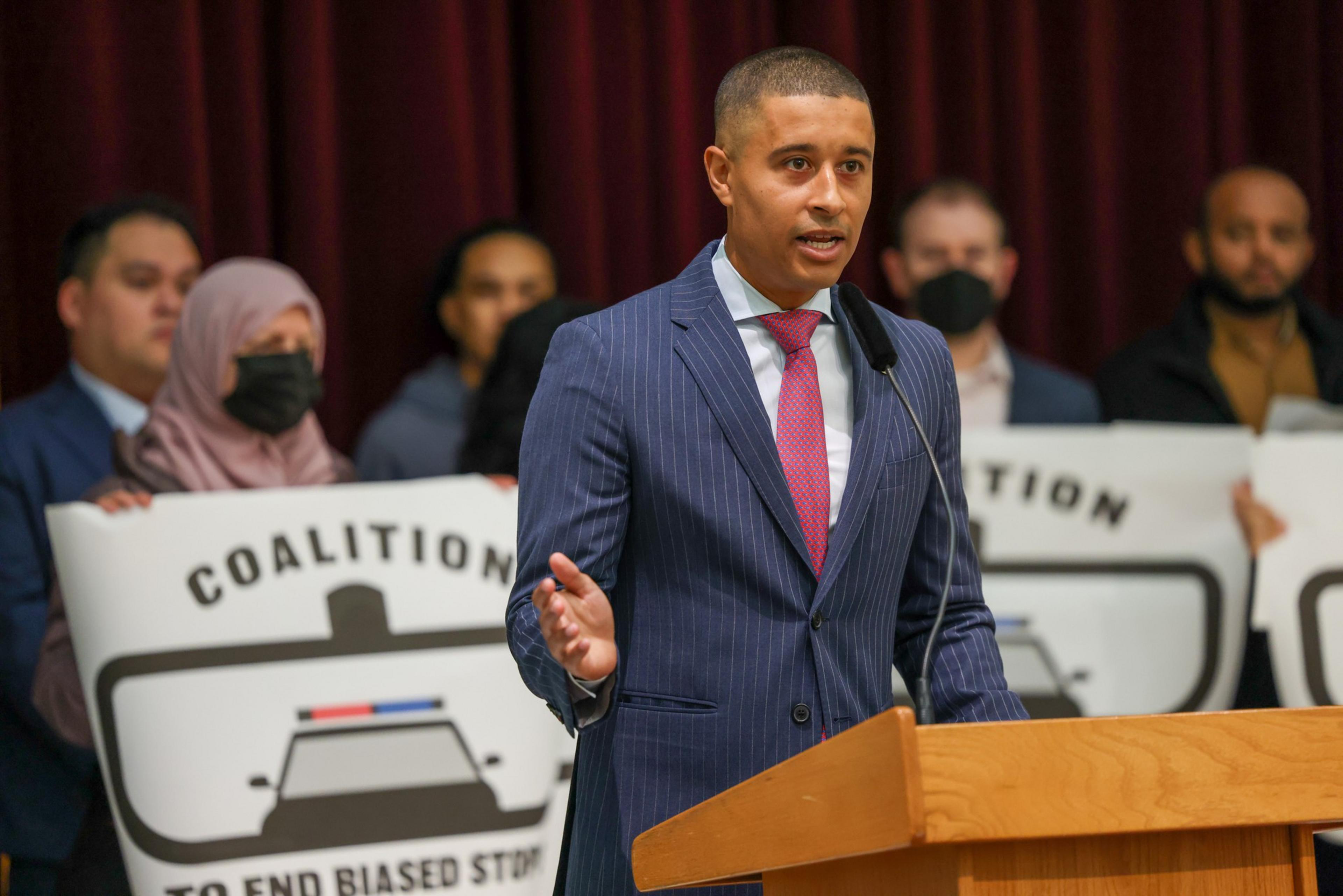A man in a suit speaks at a podium.