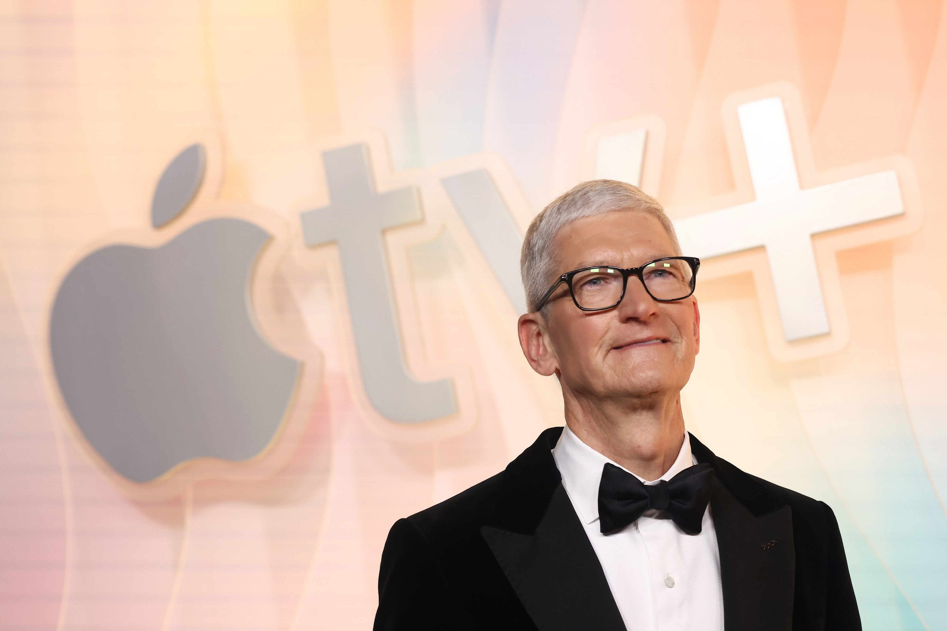 A man with gray hair and black glasses wears a black tuxedo and bow tie ...