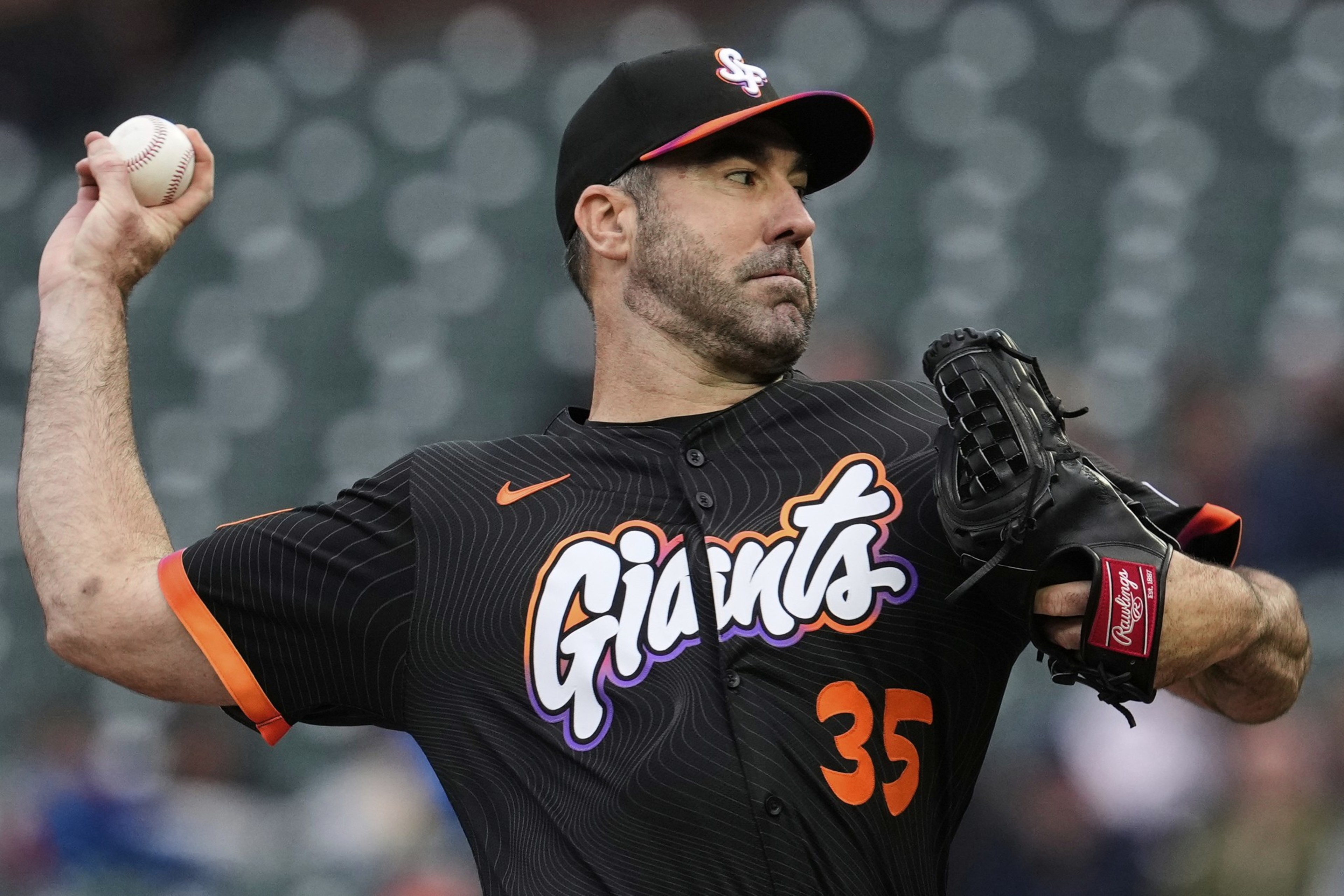 A baseball player is pitching, wearing a black "Giants" jersey marked number 35, with a glove on his left hand and holding a ball in the other.