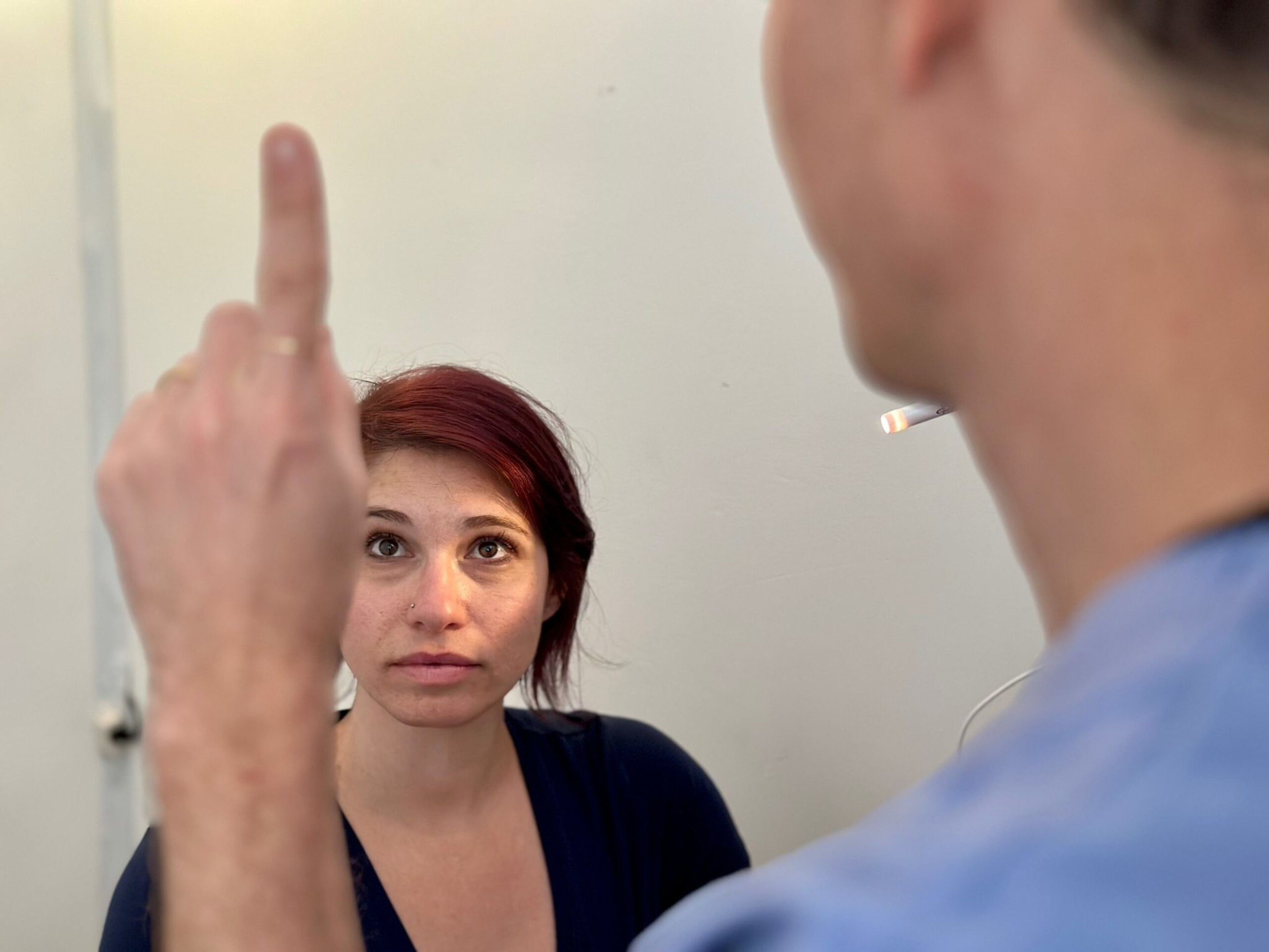 A woman with red hair looks up seriously at a man holding up his middle finger, who has a cigarette in his mouth.