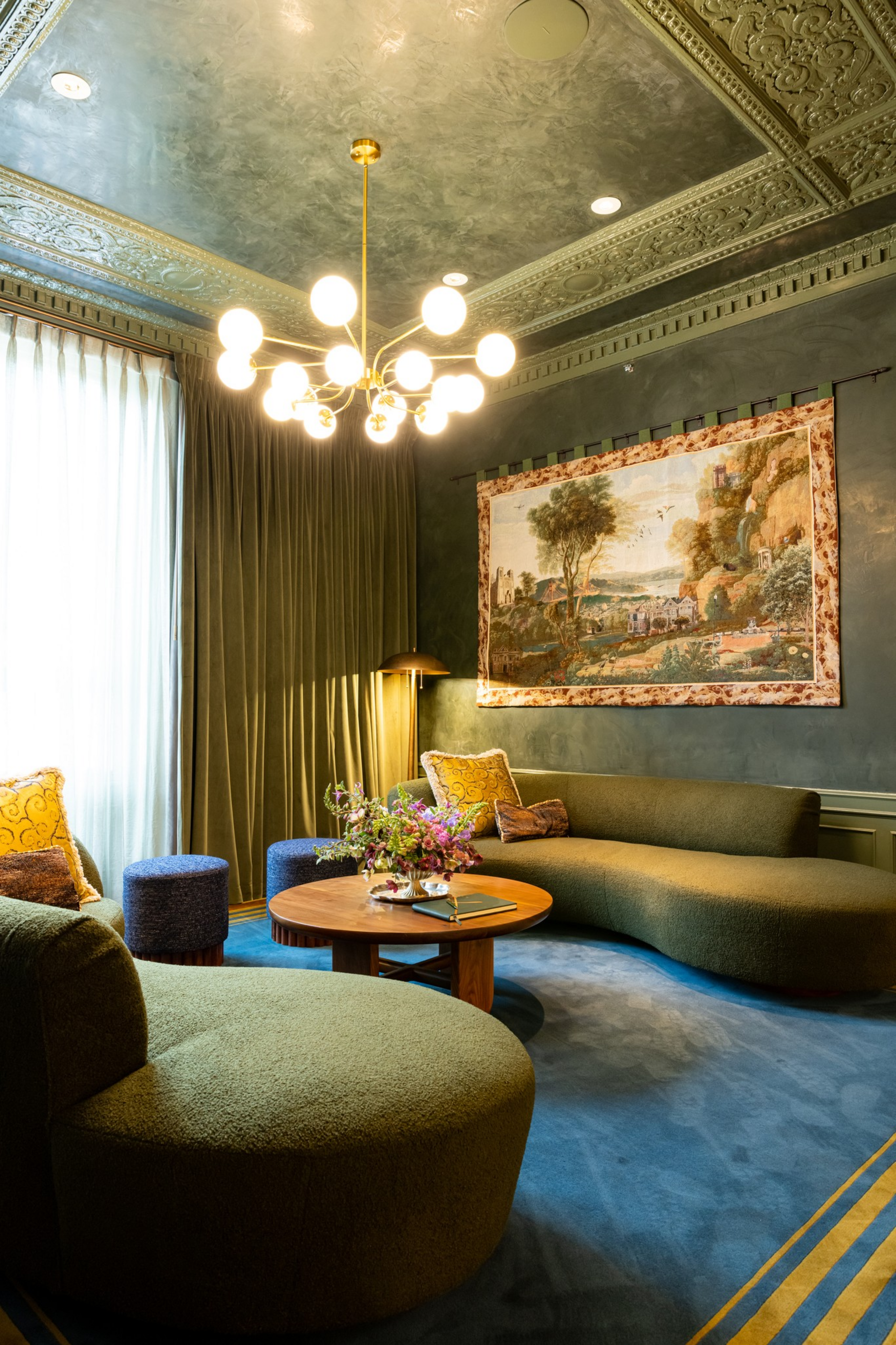 A cozy living room features olive-green curved sofas, a round wooden ...