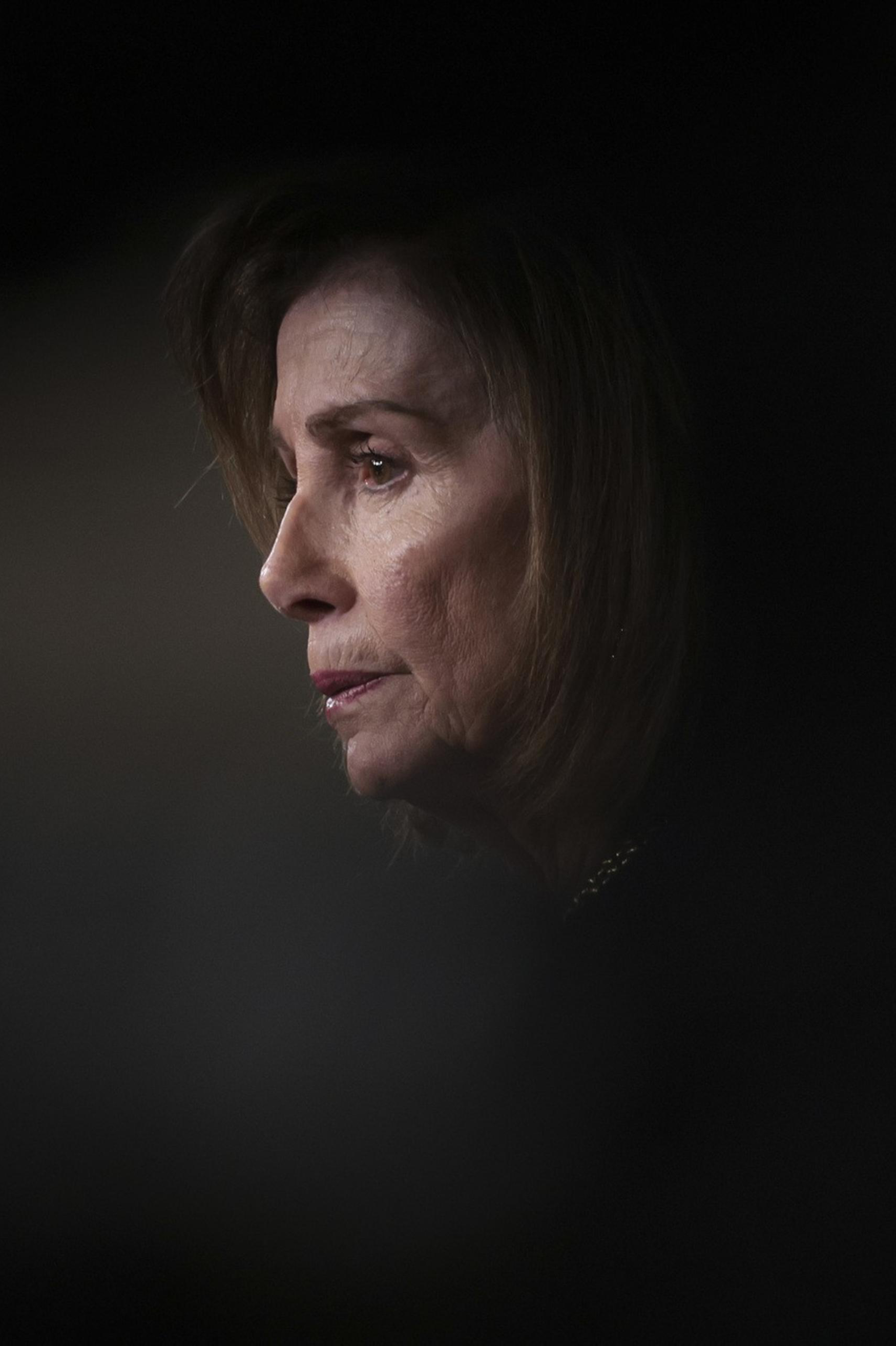 A person is seen in profile with soft lighting highlighting their face against a dark, blurred background. The expression appears contemplative.