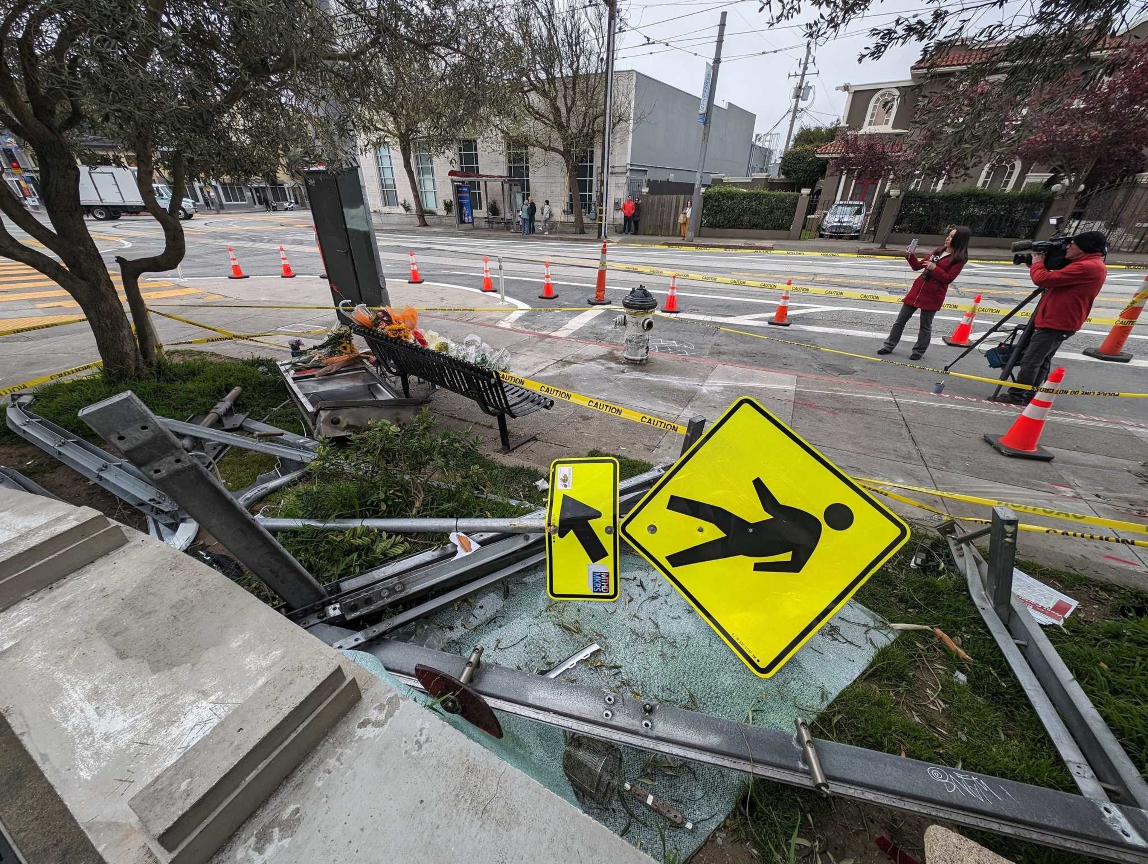 A sign and other metal objects lay twisted on the ground next to a sidewalk.