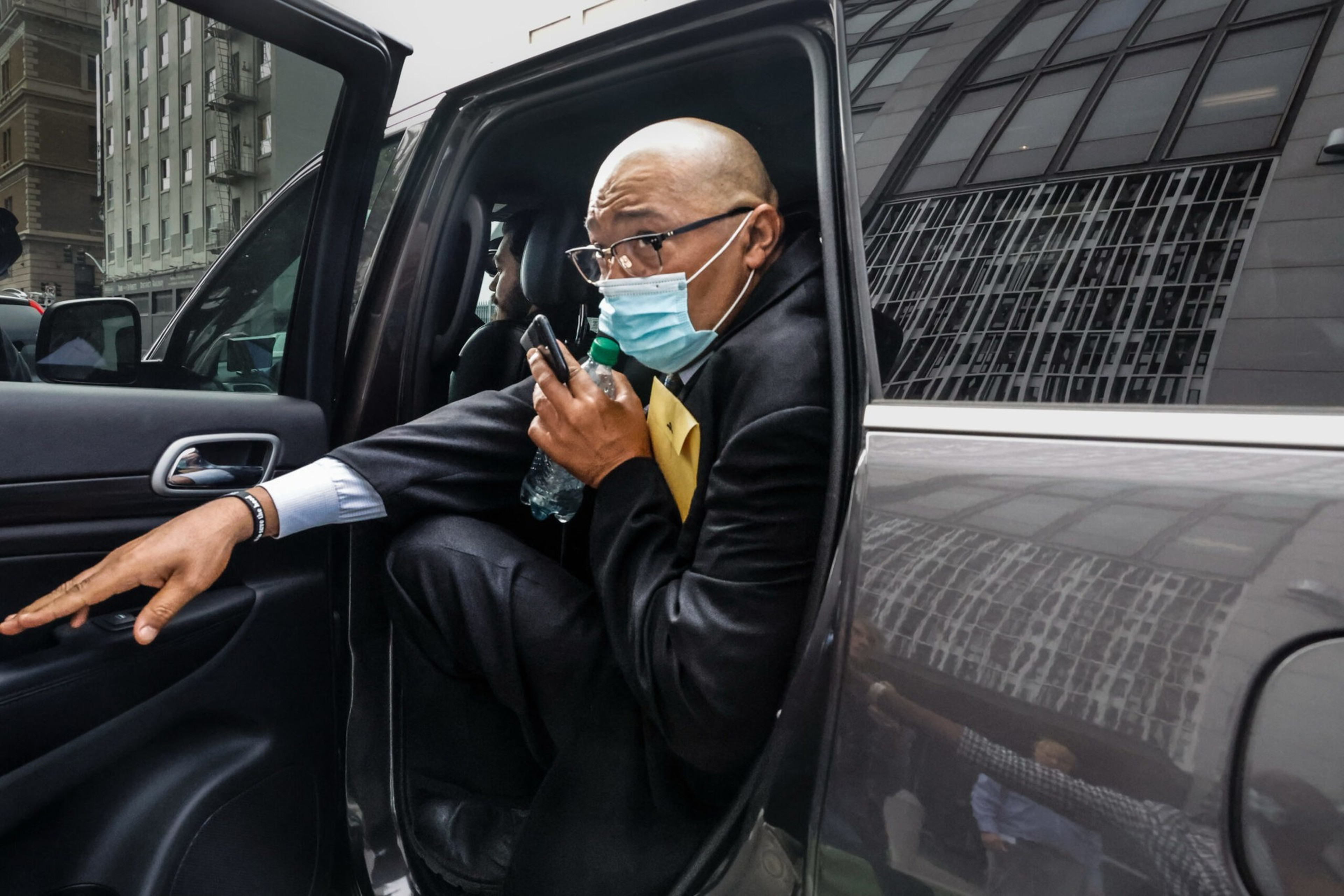 Mohammed Nuru, wearing a black suit, gets into a waiting SUV after leaving court.