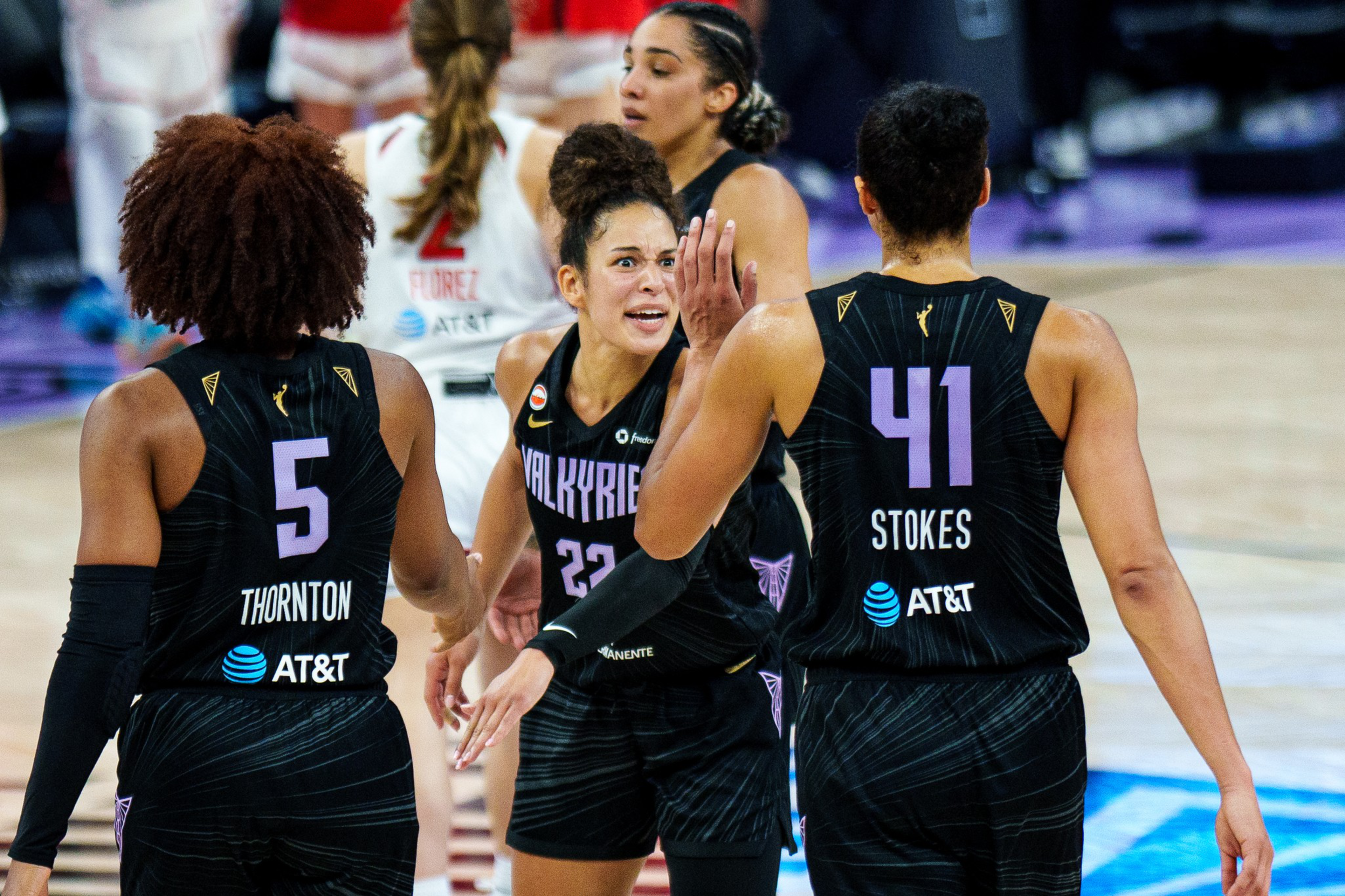 Three basketball players in black “Valkyrie” uniforms are celebrating, with the middle player showing an intense expression and two others raising hands.