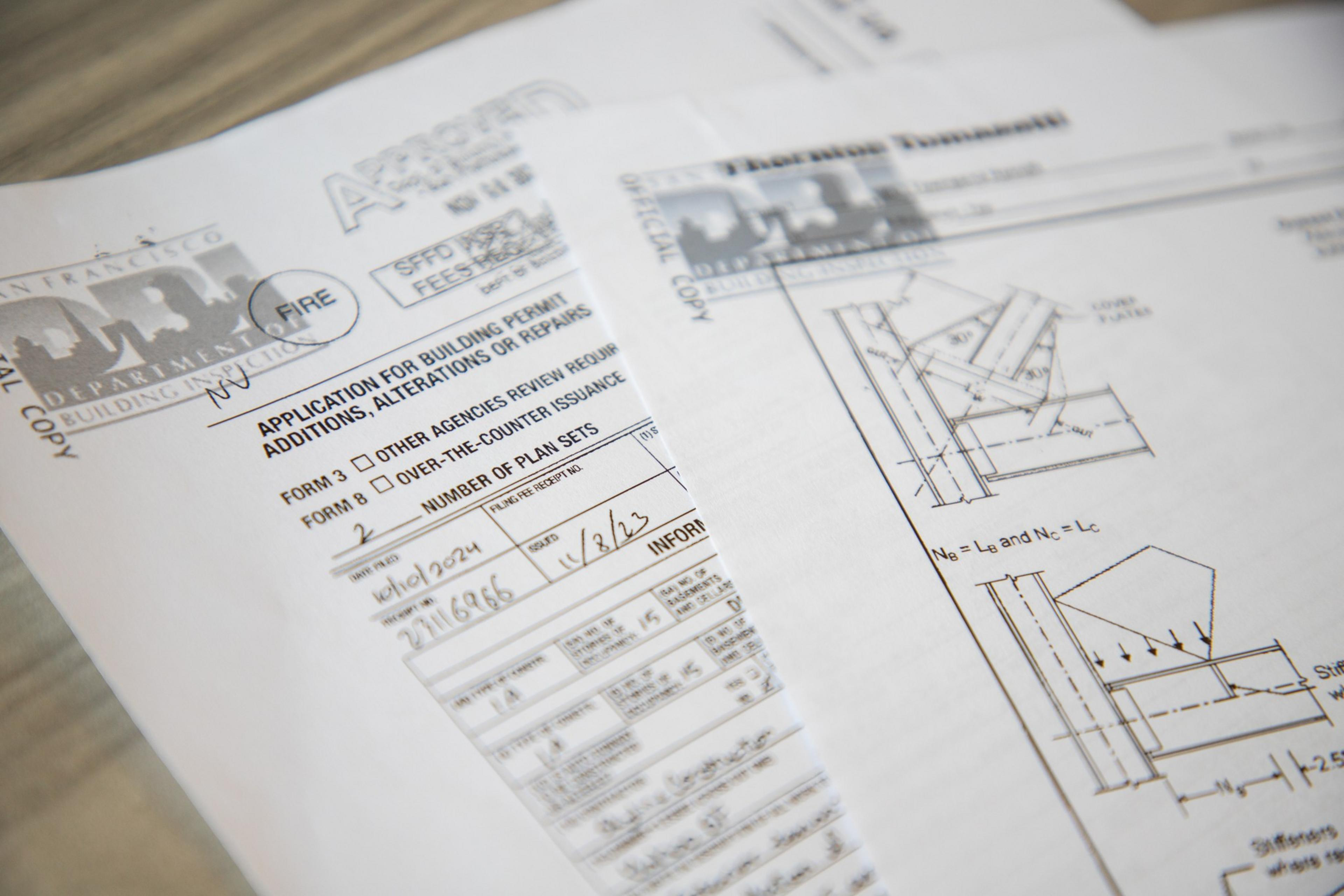 The image shows architectural blueprints and a building permit application form.