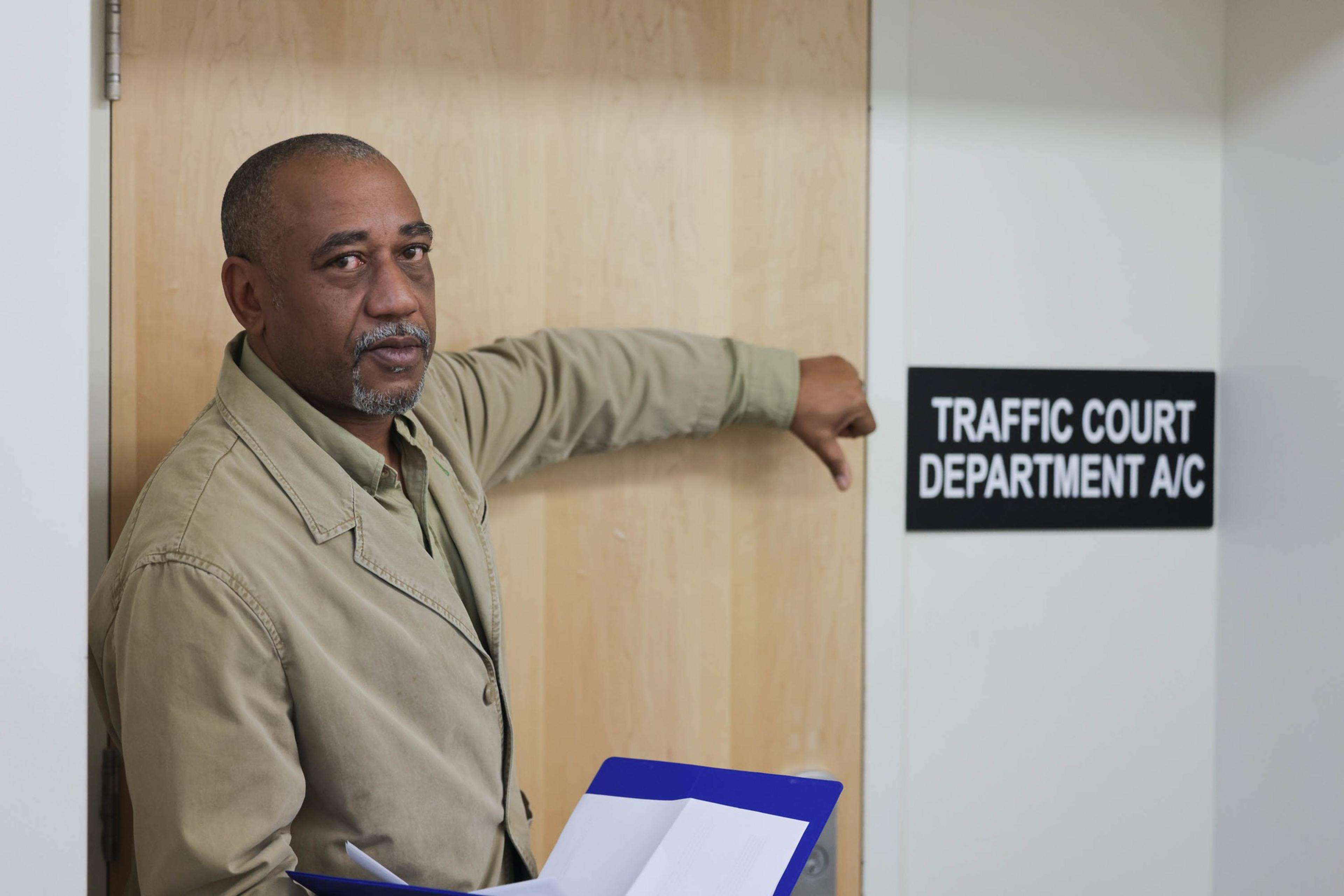 A person gives the thumbs down to a sign that says &quot;traffic court department A&quot;.