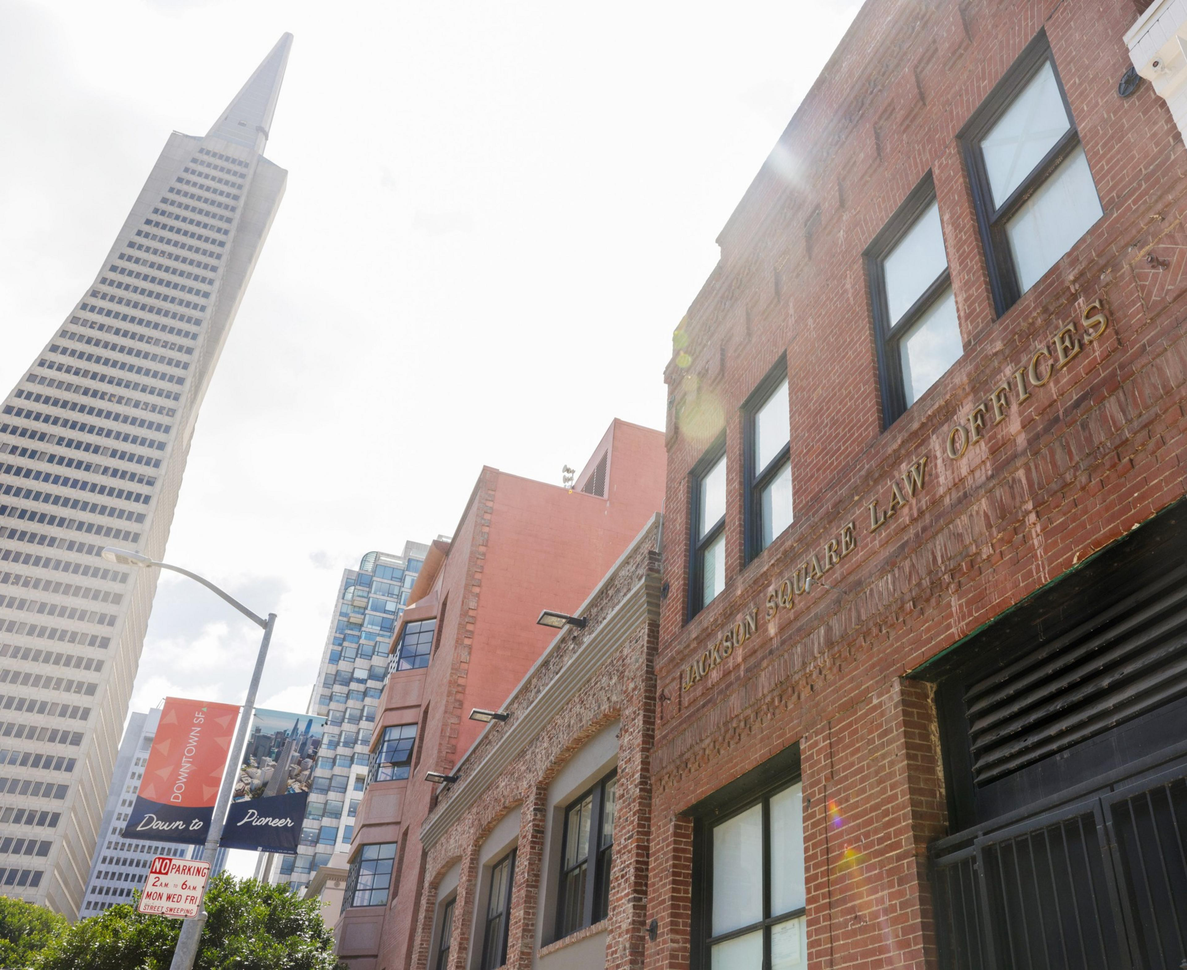 A cityscape with a mix of old brick buildings and modern skyscrapers under a clear sky.