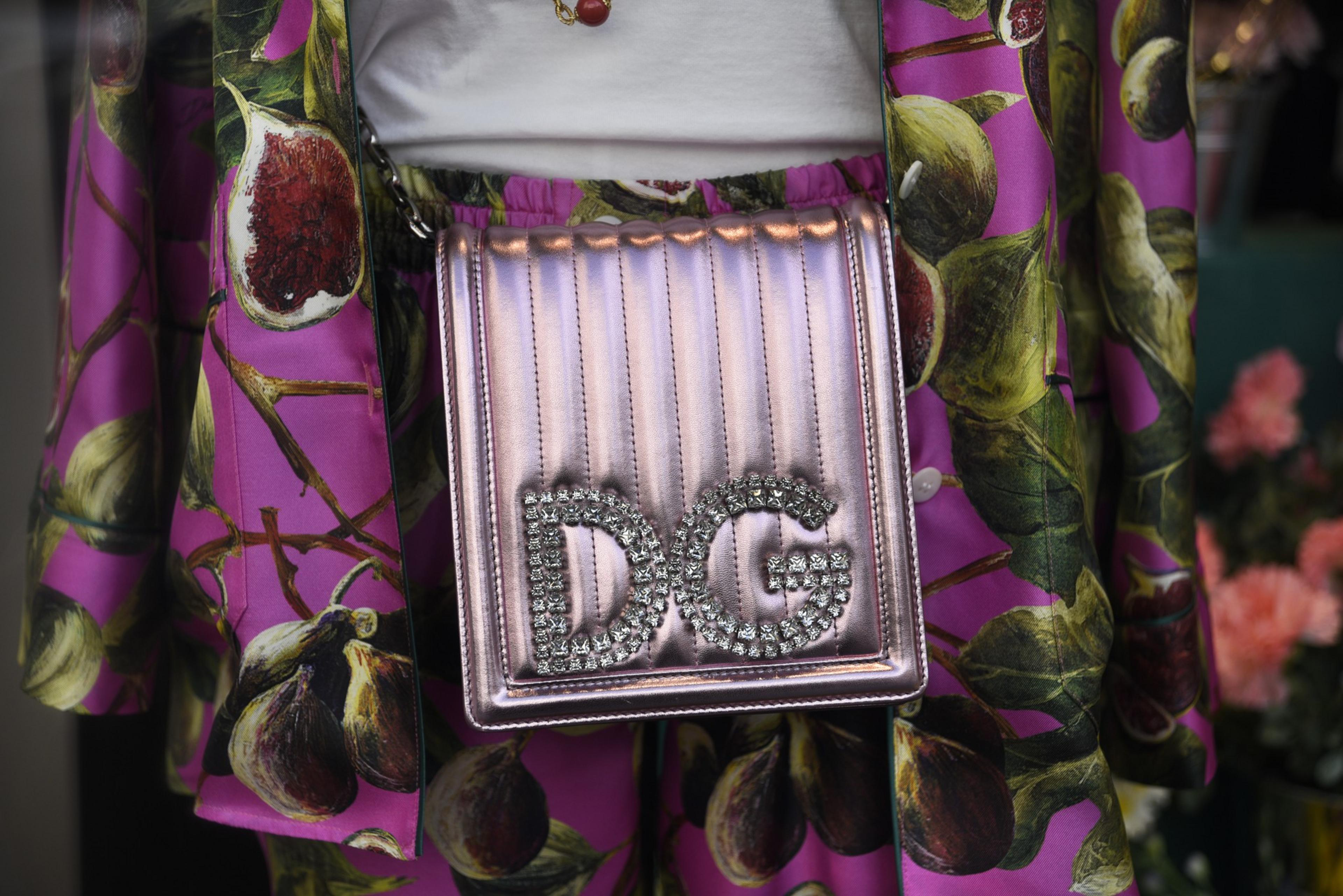 A pink metallic bag with &quot;DG&quot; in rhinestones over a fig-patterned skirt and jacket set.