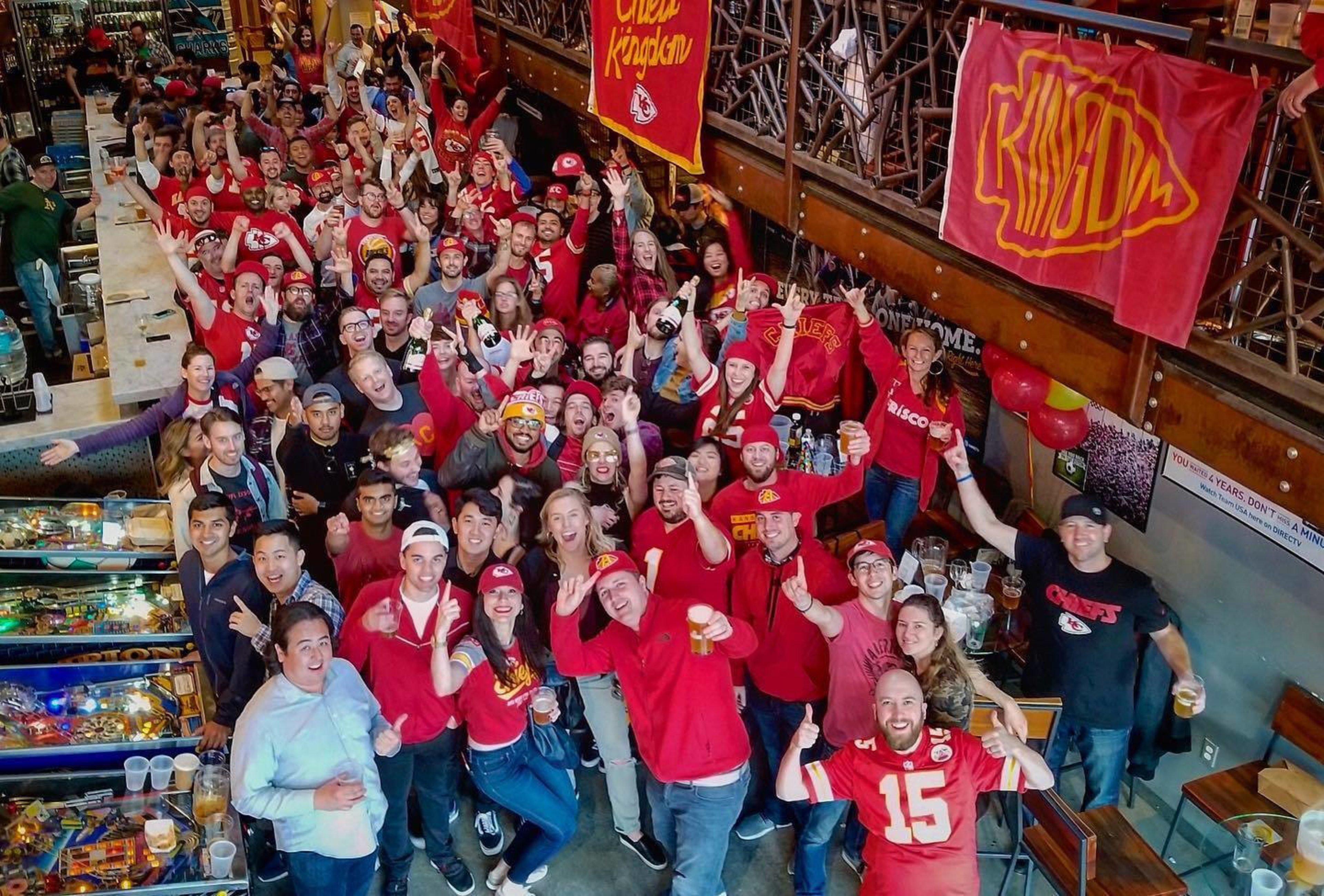 Dressed in red jerseys and shirts, Kansas City Chief football fans cheer in a bar in SoMa's San Francisco neighborhood. 