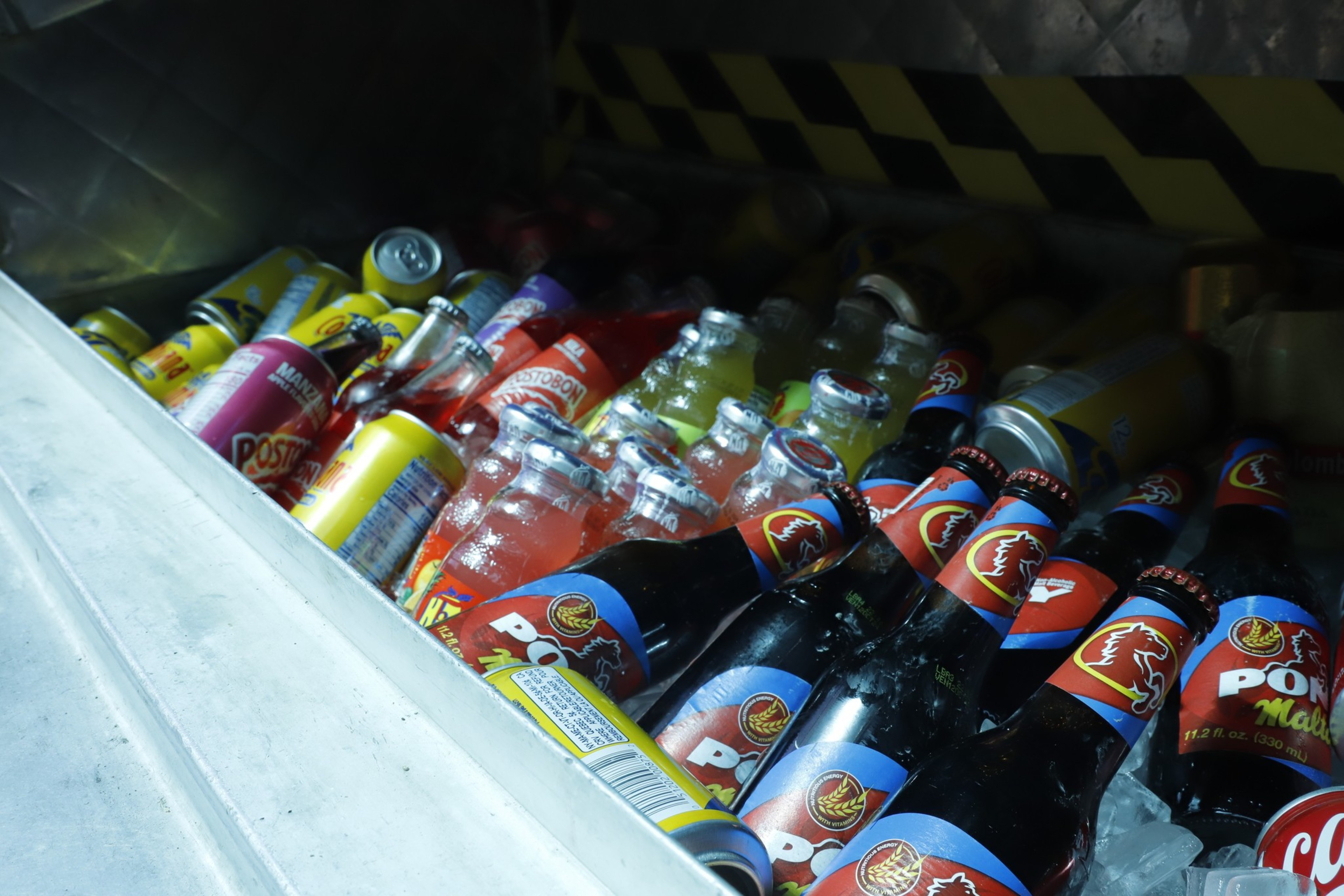 A cooler filled with assorted colorful beverage cans and bottles on ice.