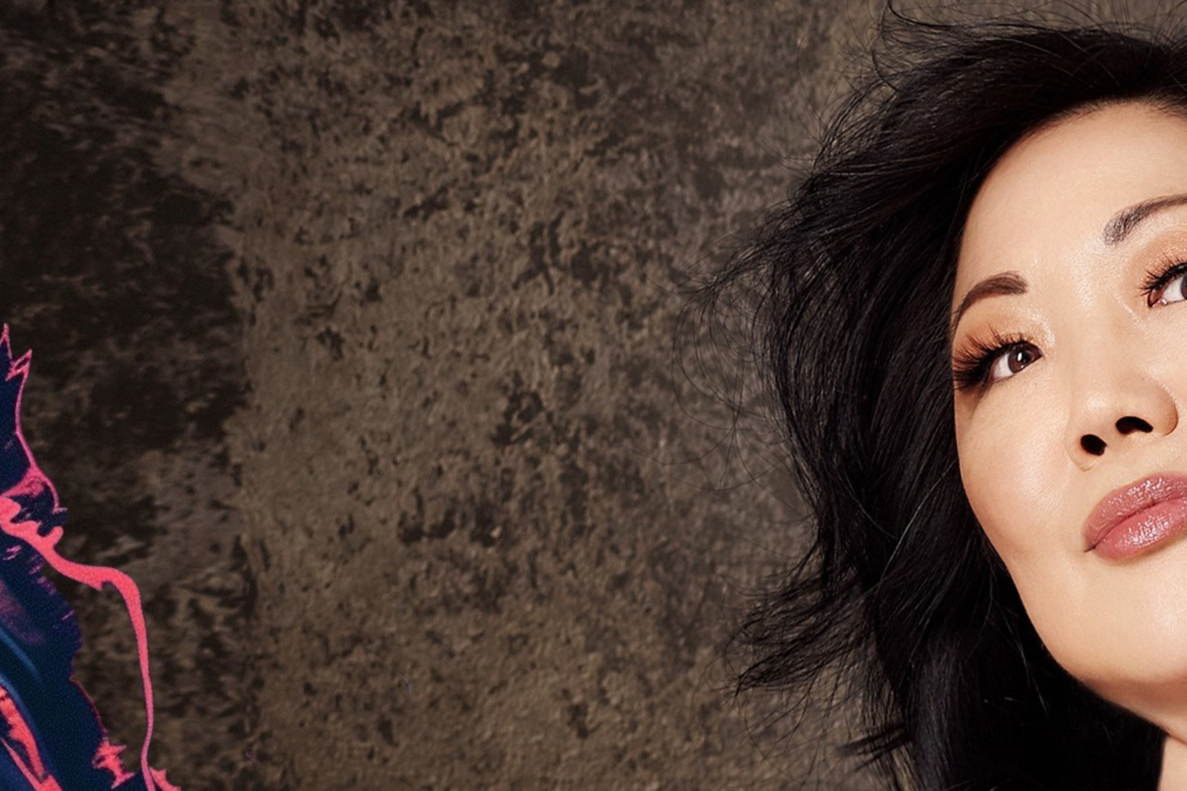 Margaret Cho poses in a black tank top, showing off the color tattoos on her arms.