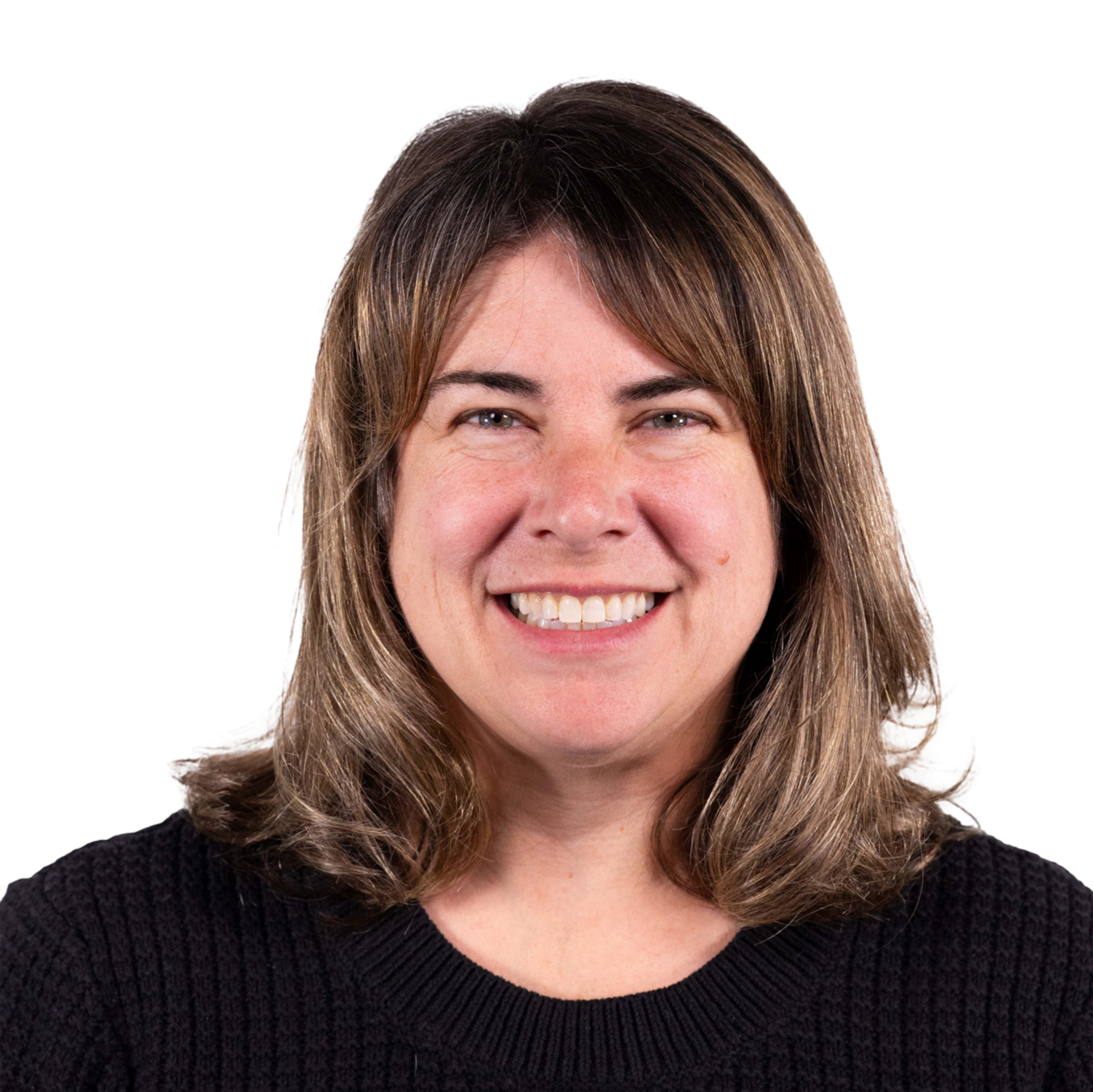 A woman with shoulder-length brown hair and light highlights smiles warmly, wearing a black textured sweater against a plain background.